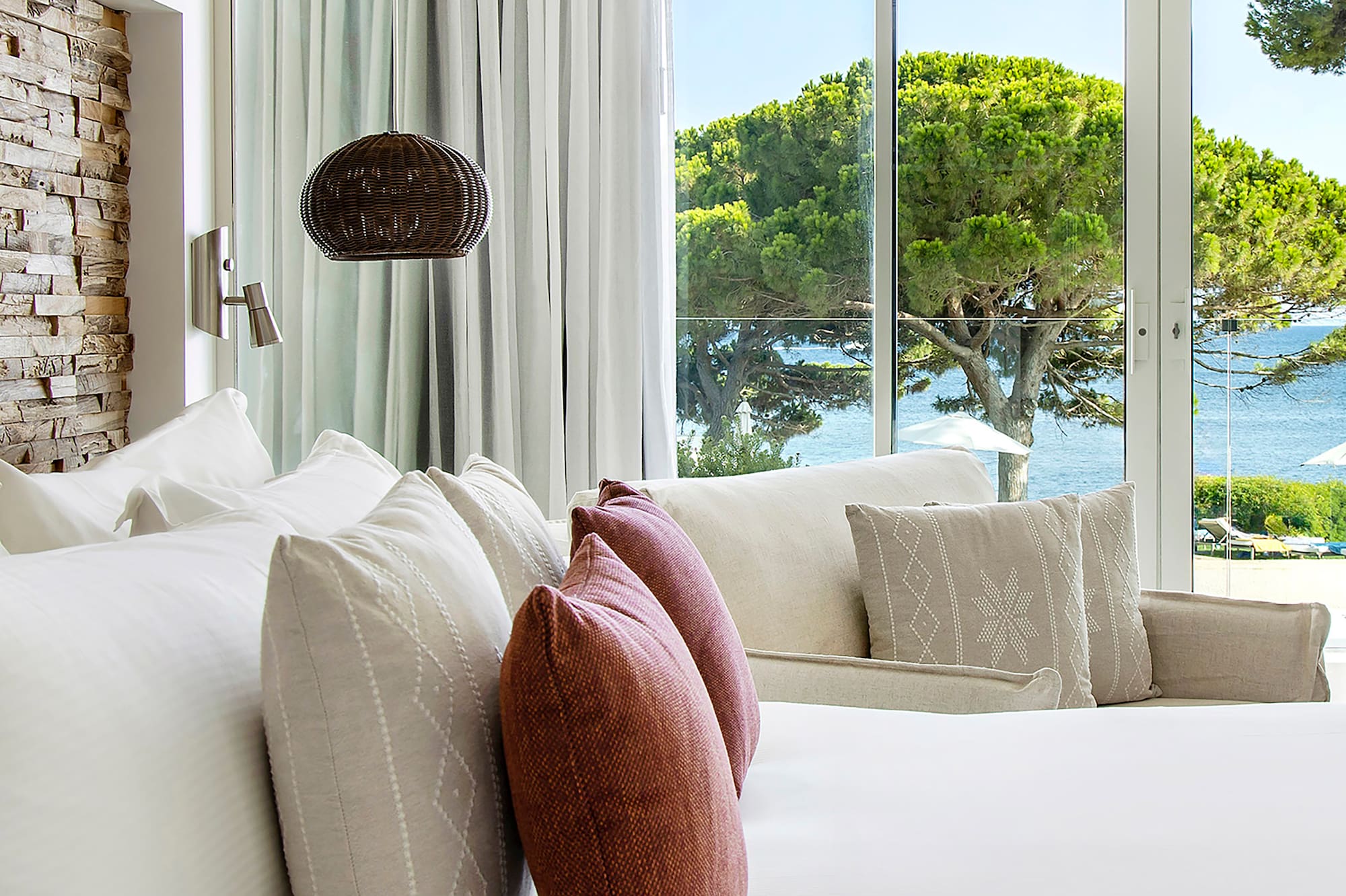 a bed with pillows and a lamp in front of a large window