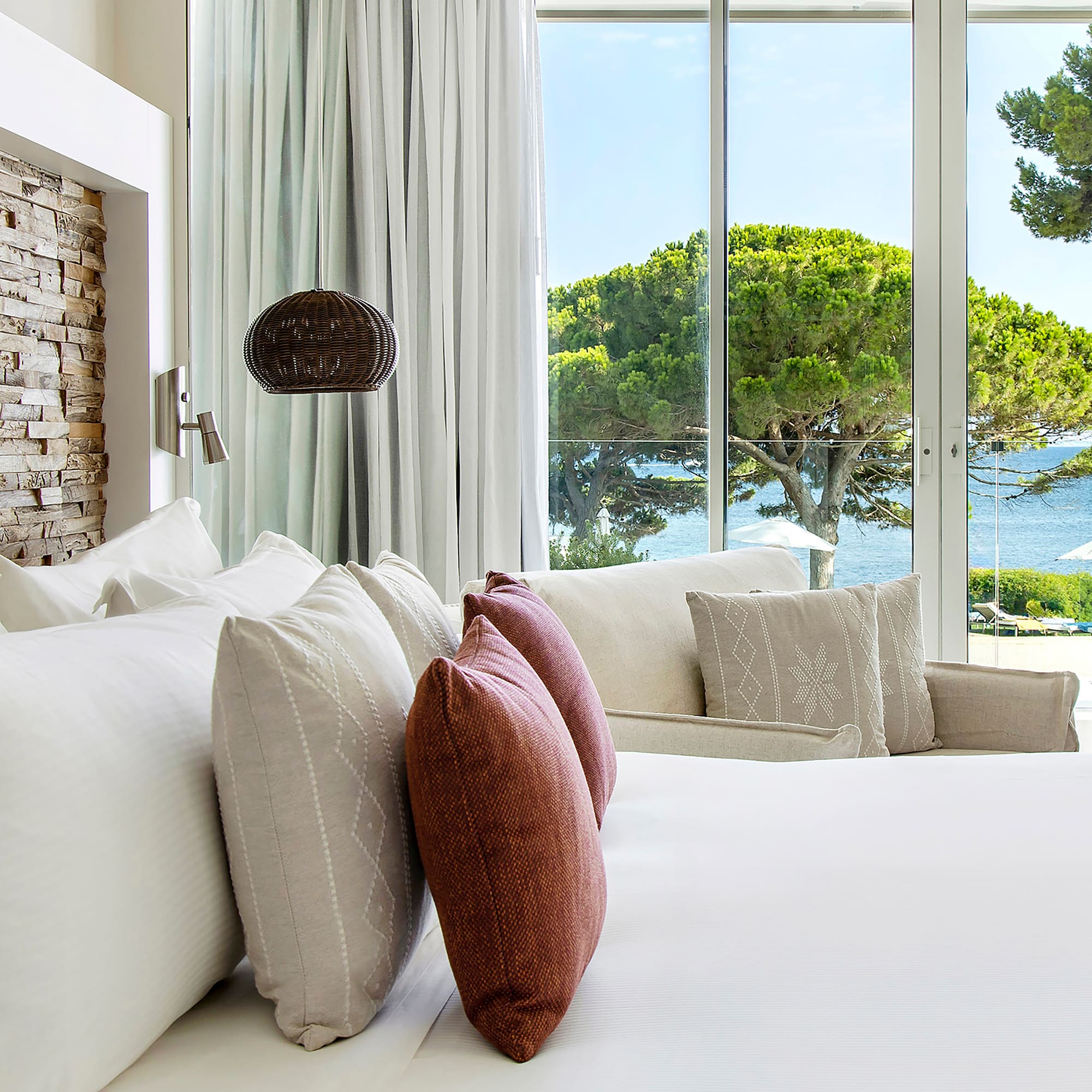 a bed with pillows and a lamp in front of a large window