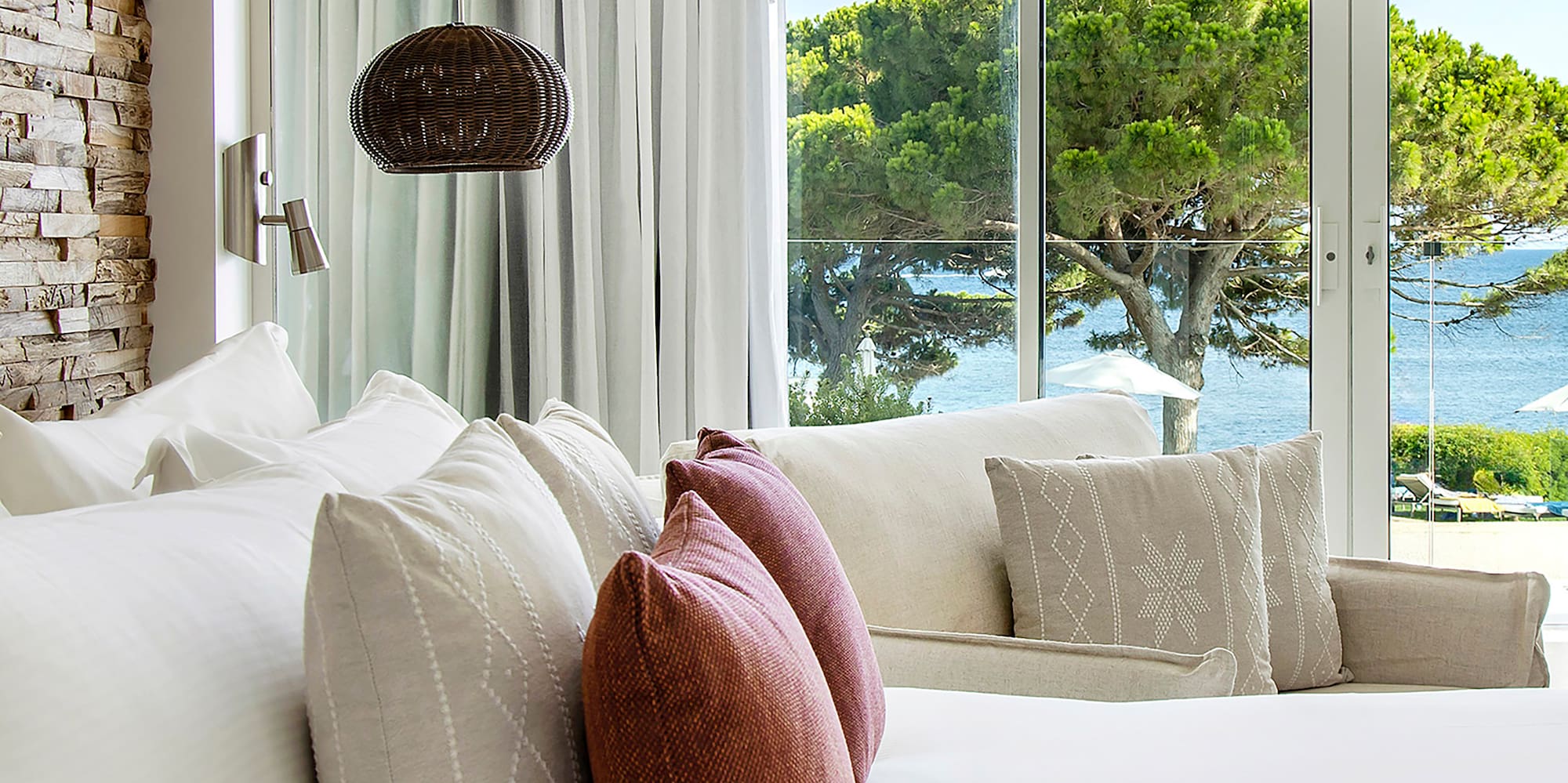 a bed with pillows and a lamp in front of a large window