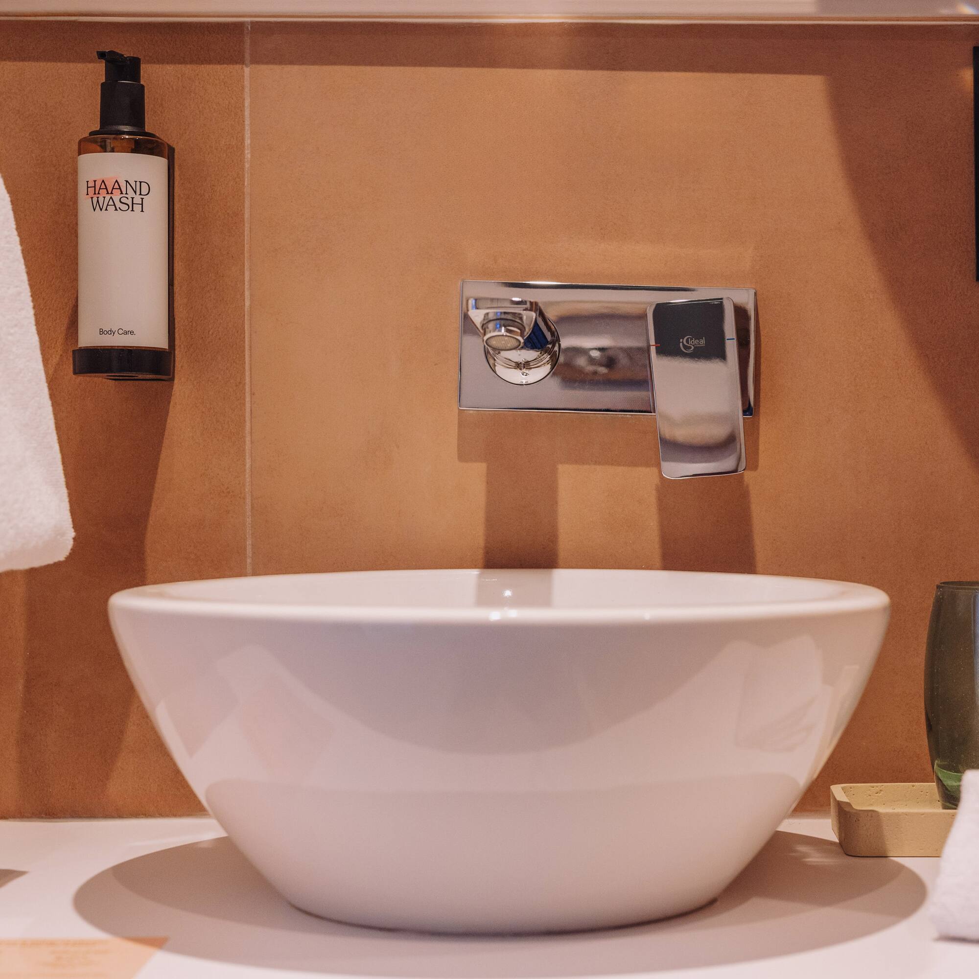 a white sink with a silver faucet and a bottle of soap