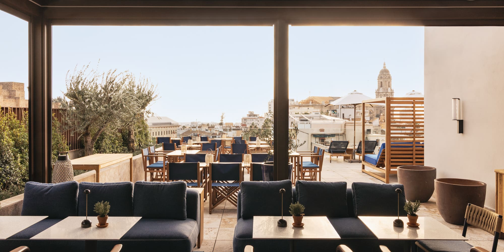 Rooftop terrace lounge and dining with blue seating and city skyline view.