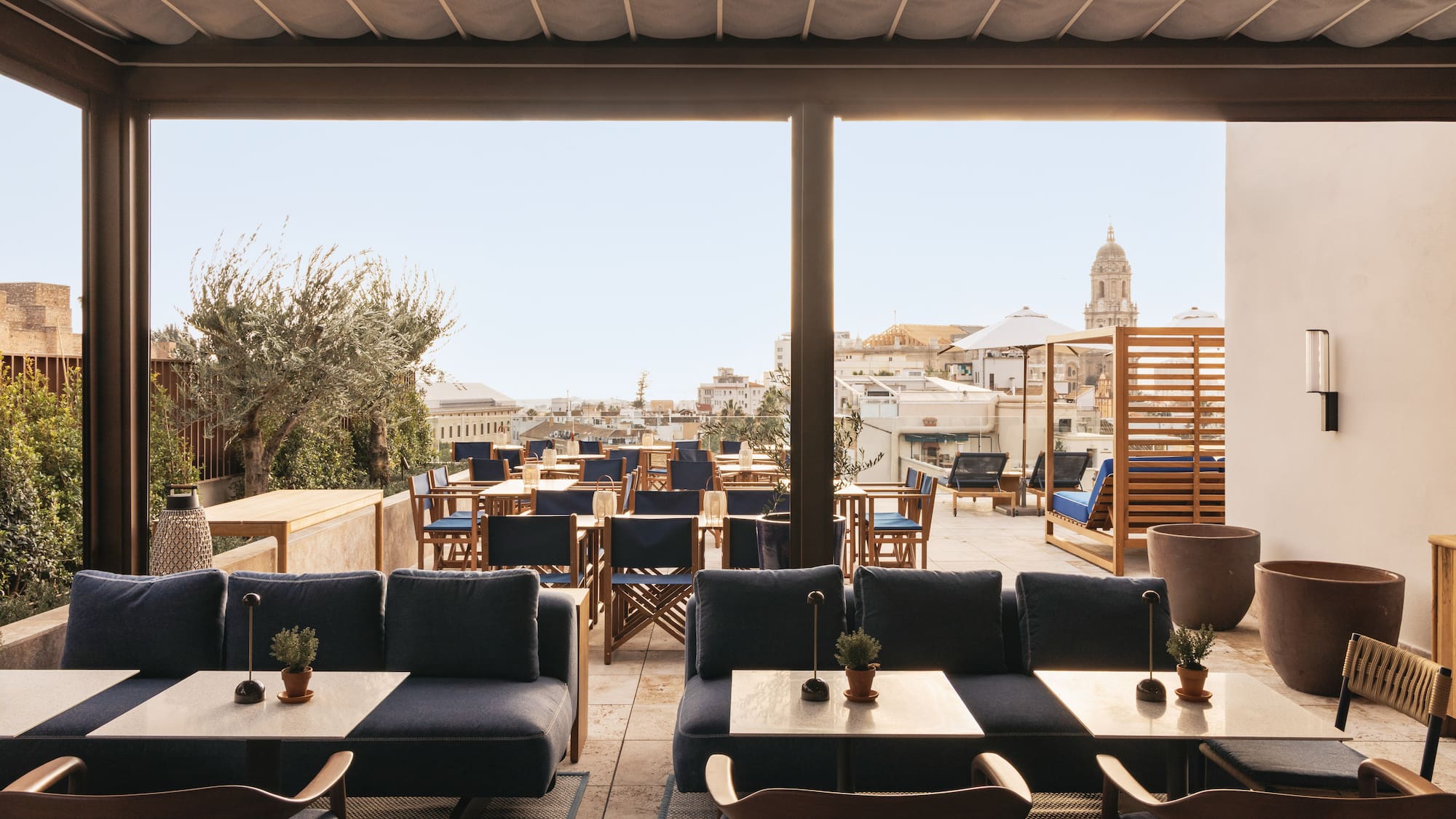 Rooftop terrace lounge and dining with blue seating and city skyline view.
