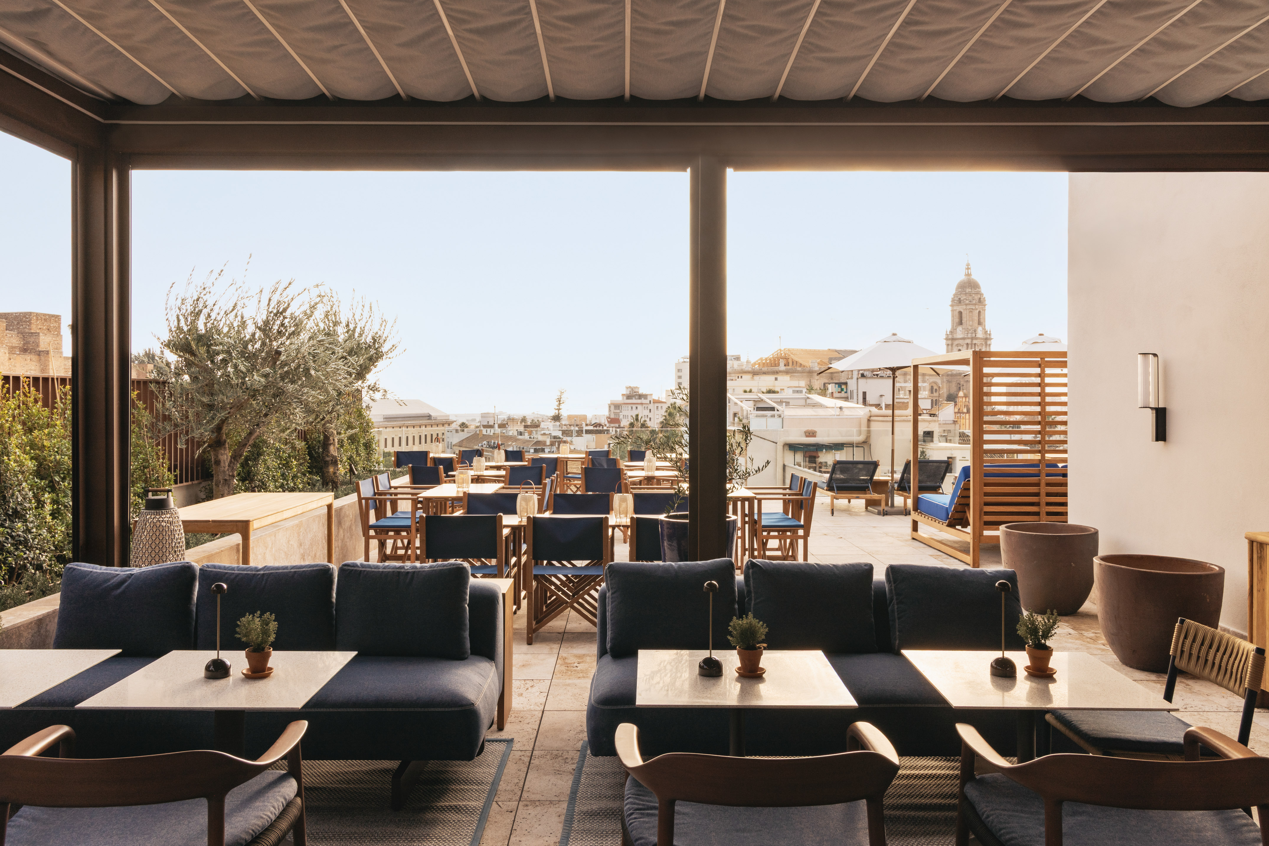 Rooftop terrace lounge and dining with blue seating and city skyline view.