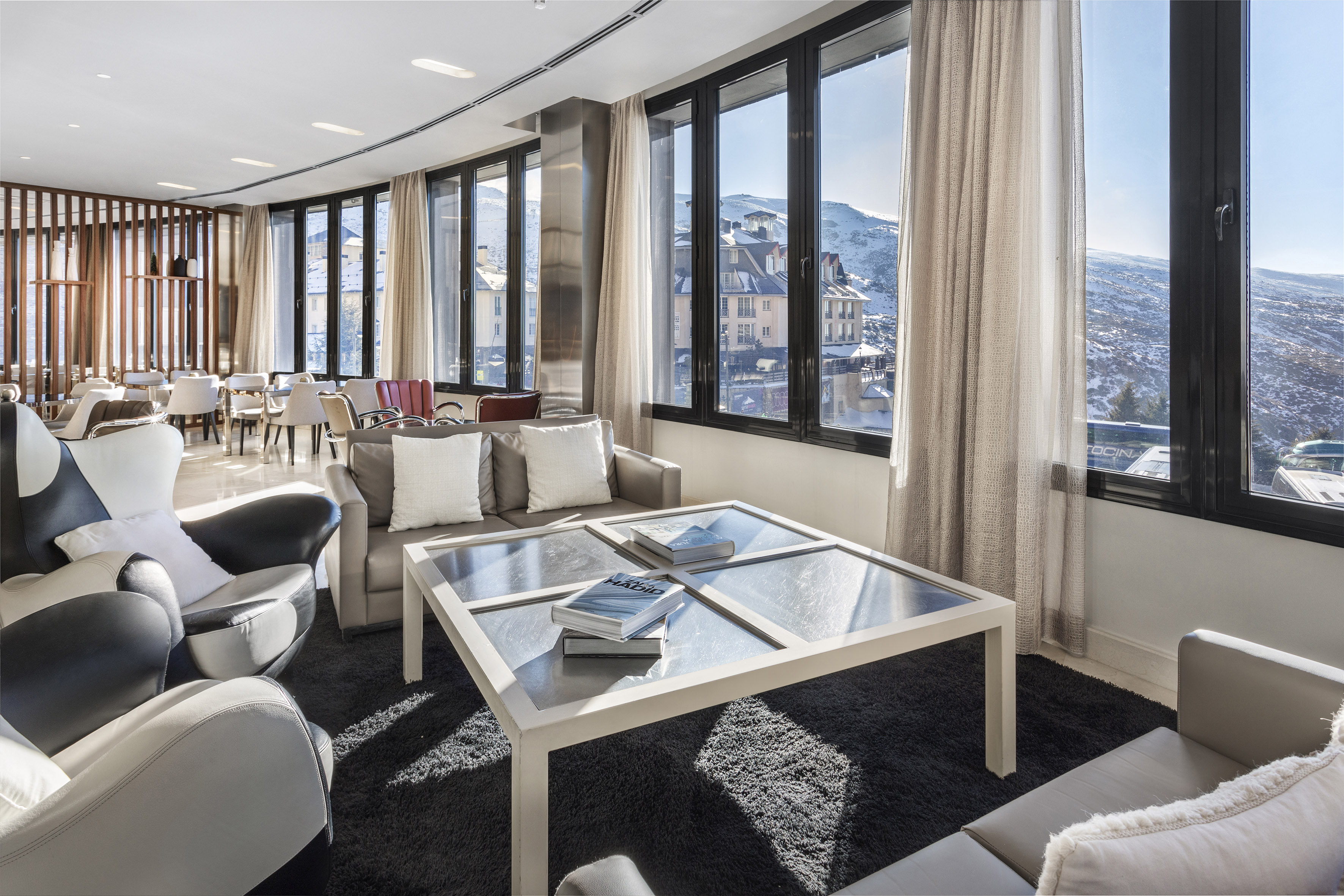 Modern hotel lounge overlooking snowy mountains, large windows, contemporary design.
