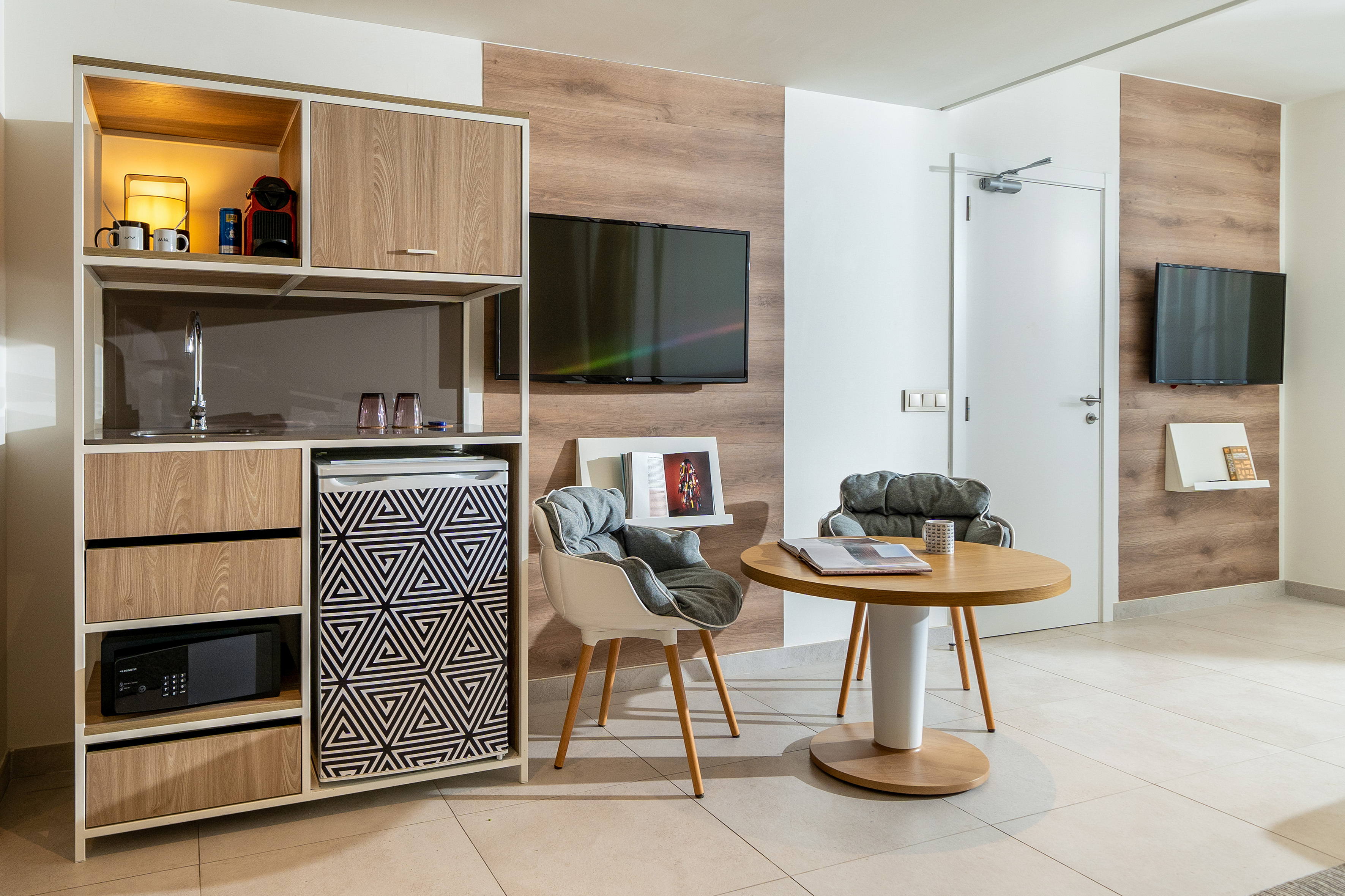 Modern studio apartment with kitchenette, minibar, TV, and dining furniture.