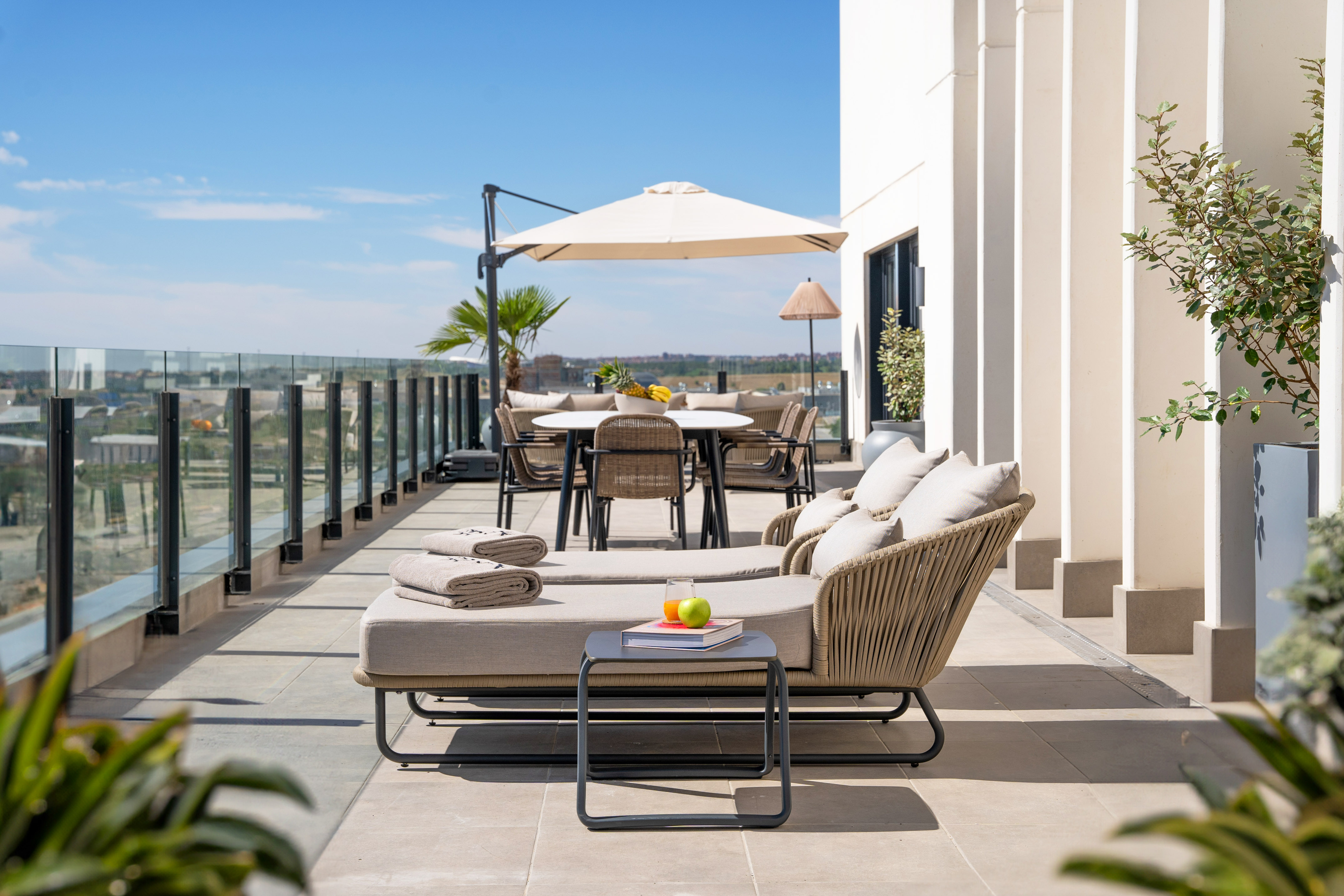 Modern rooftop terrace with outdoor lounge, dining set, and city views.