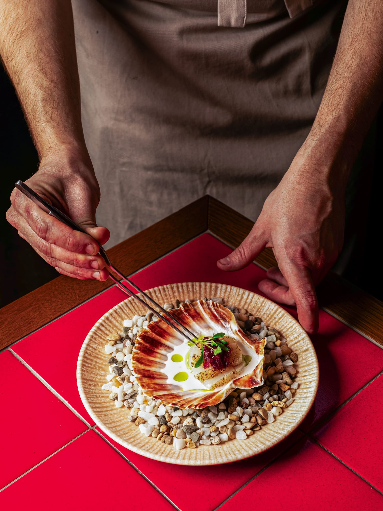 a person holding tongs to a plate of food