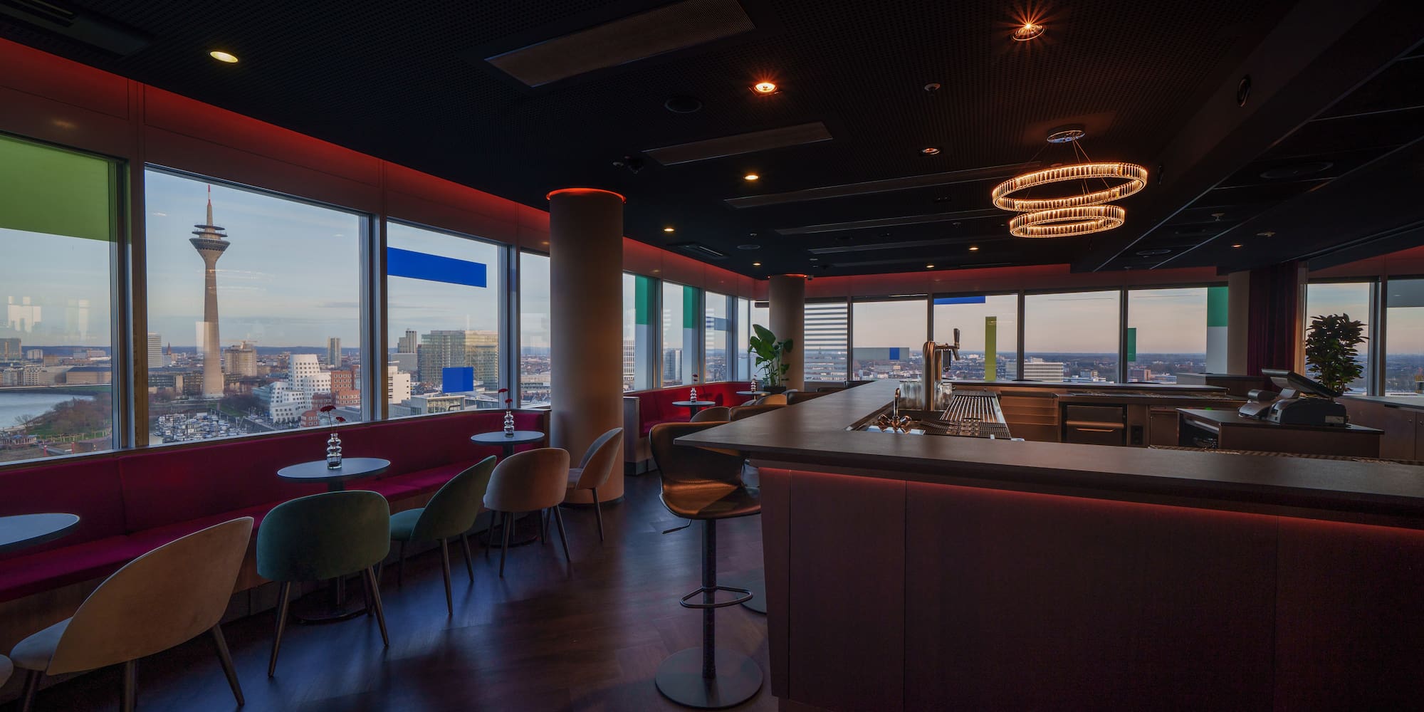 a room with a bar and chairs and a view of a city