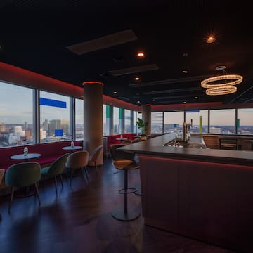 a room with a bar and chairs and a view of a city