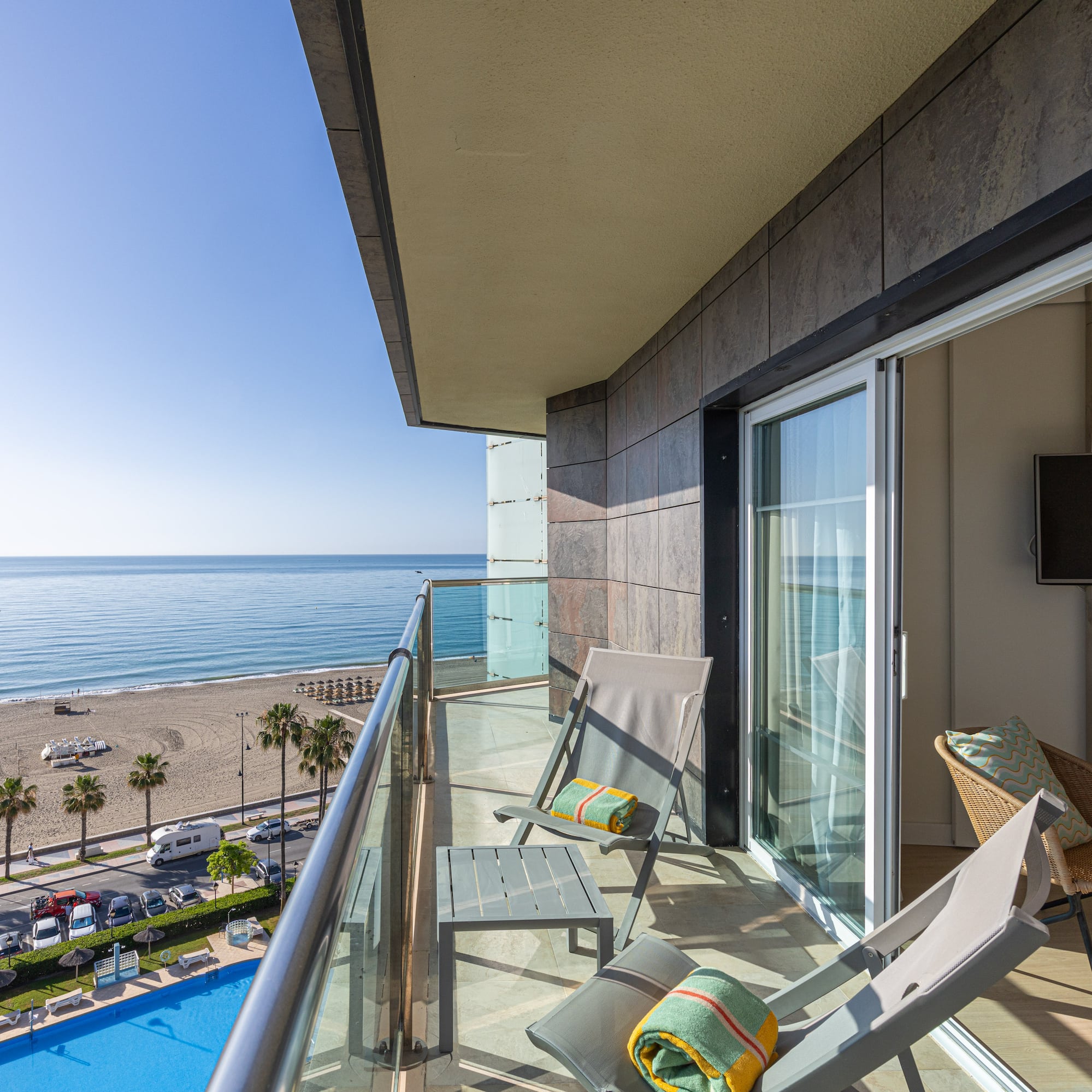 Ocean view balcony with lounge chairs, beach, and swimming pool.
