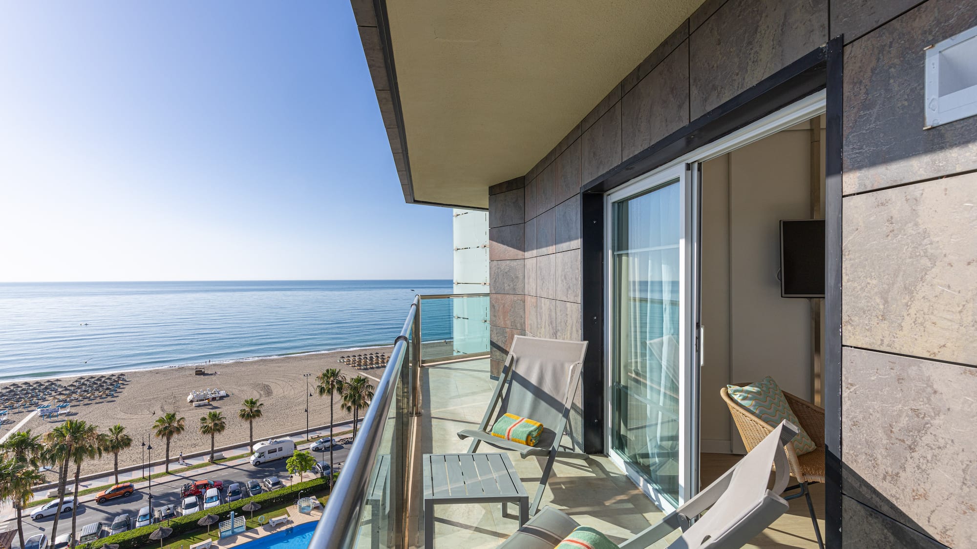Ocean view balcony with lounge chairs, beach, and swimming pool.