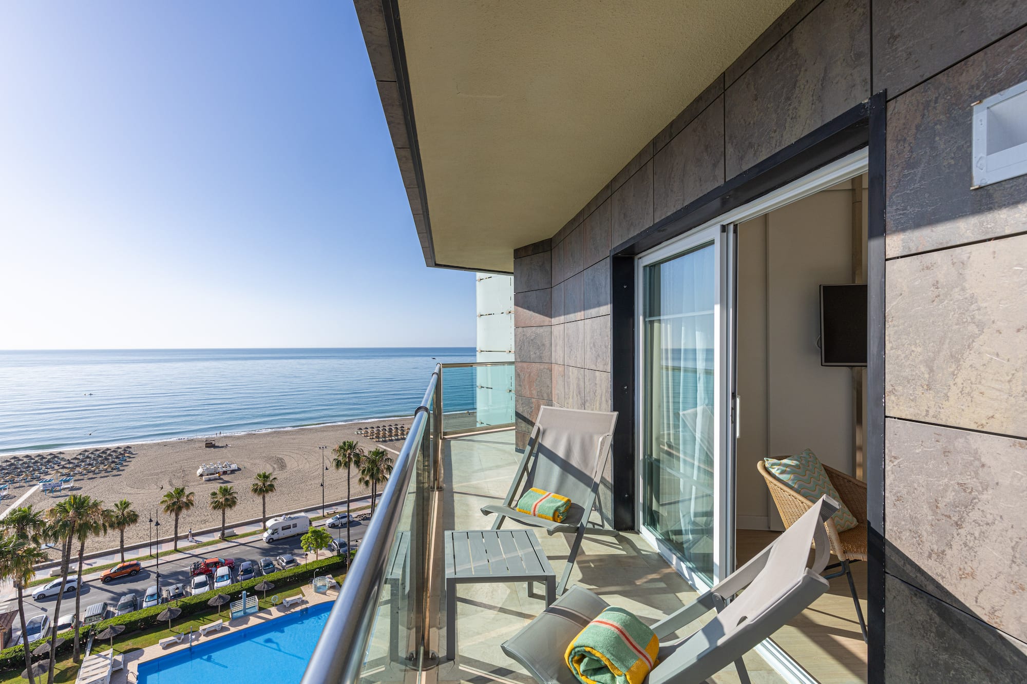 Balcony with ocean view, beach, pool, and lounge chairs.