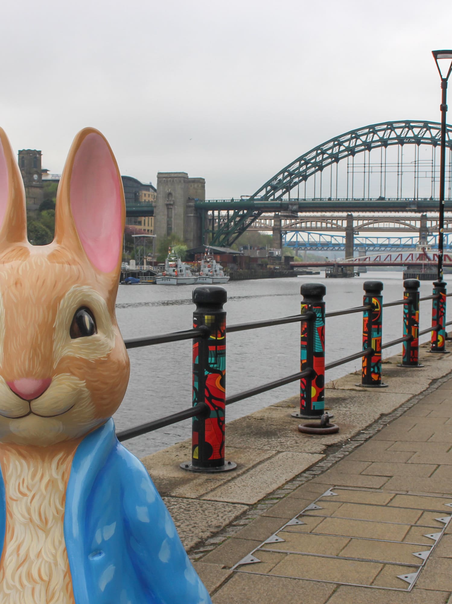 Peter Rabbit statue on Gateshead Quayside with River Tyne and Tyne Bridge.