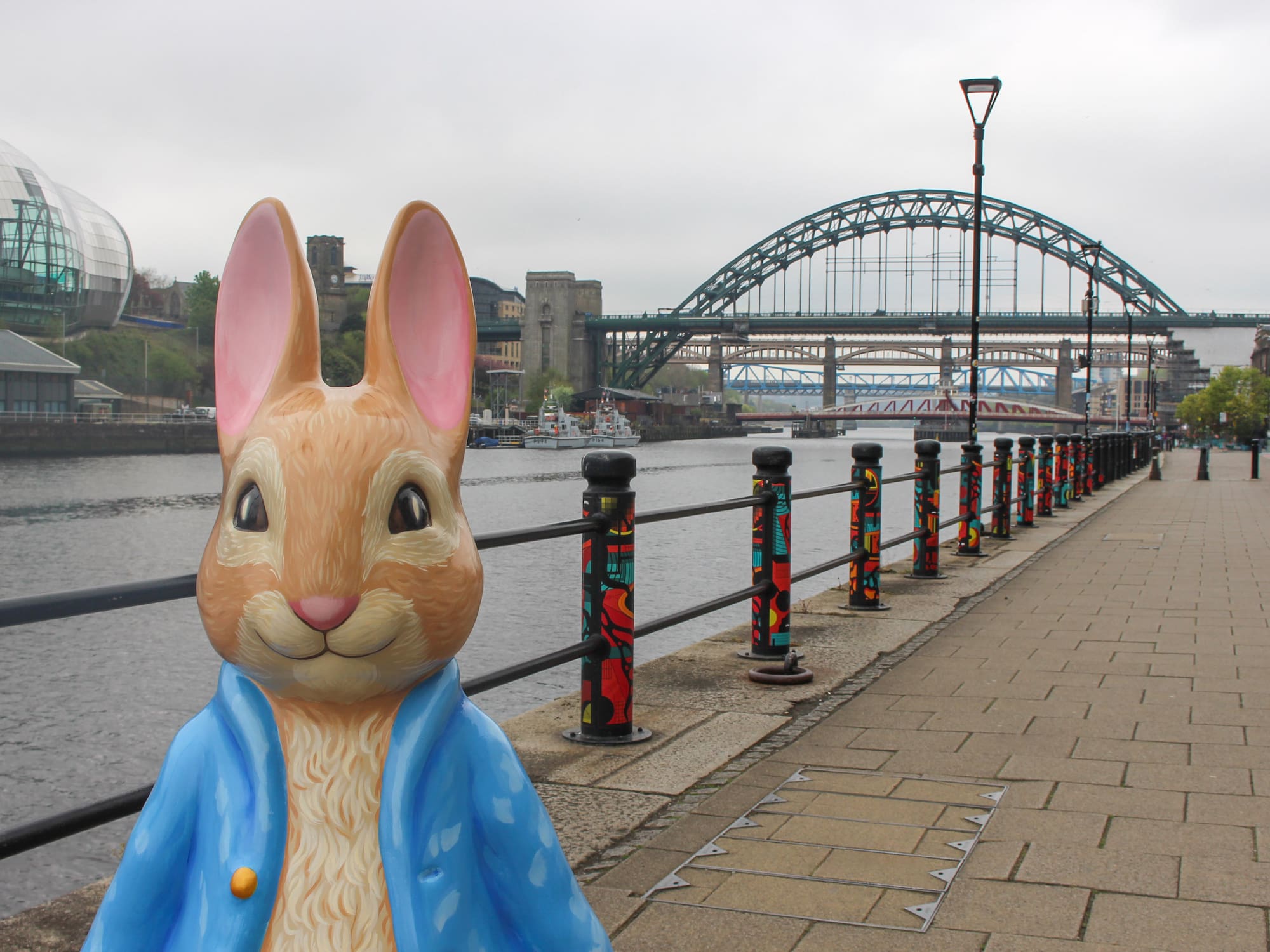 Peter Rabbit statue on Gateshead Quayside with River Tyne and Tyne Bridge.