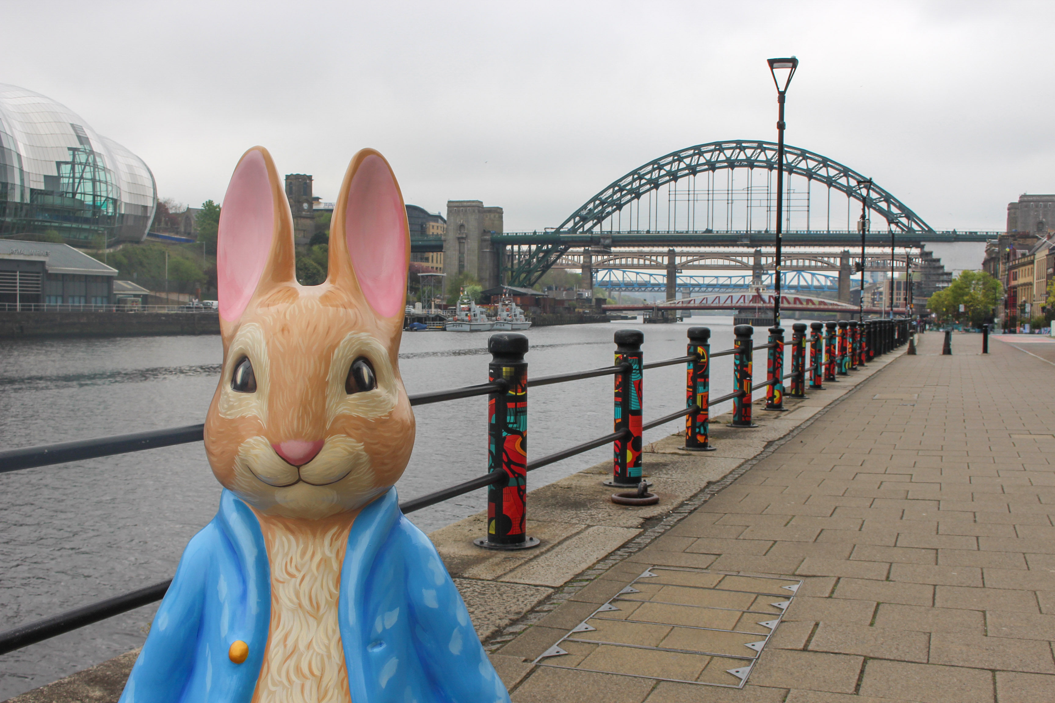 Peter Rabbit statue on Gateshead Quayside with River Tyne and Tyne Bridge.