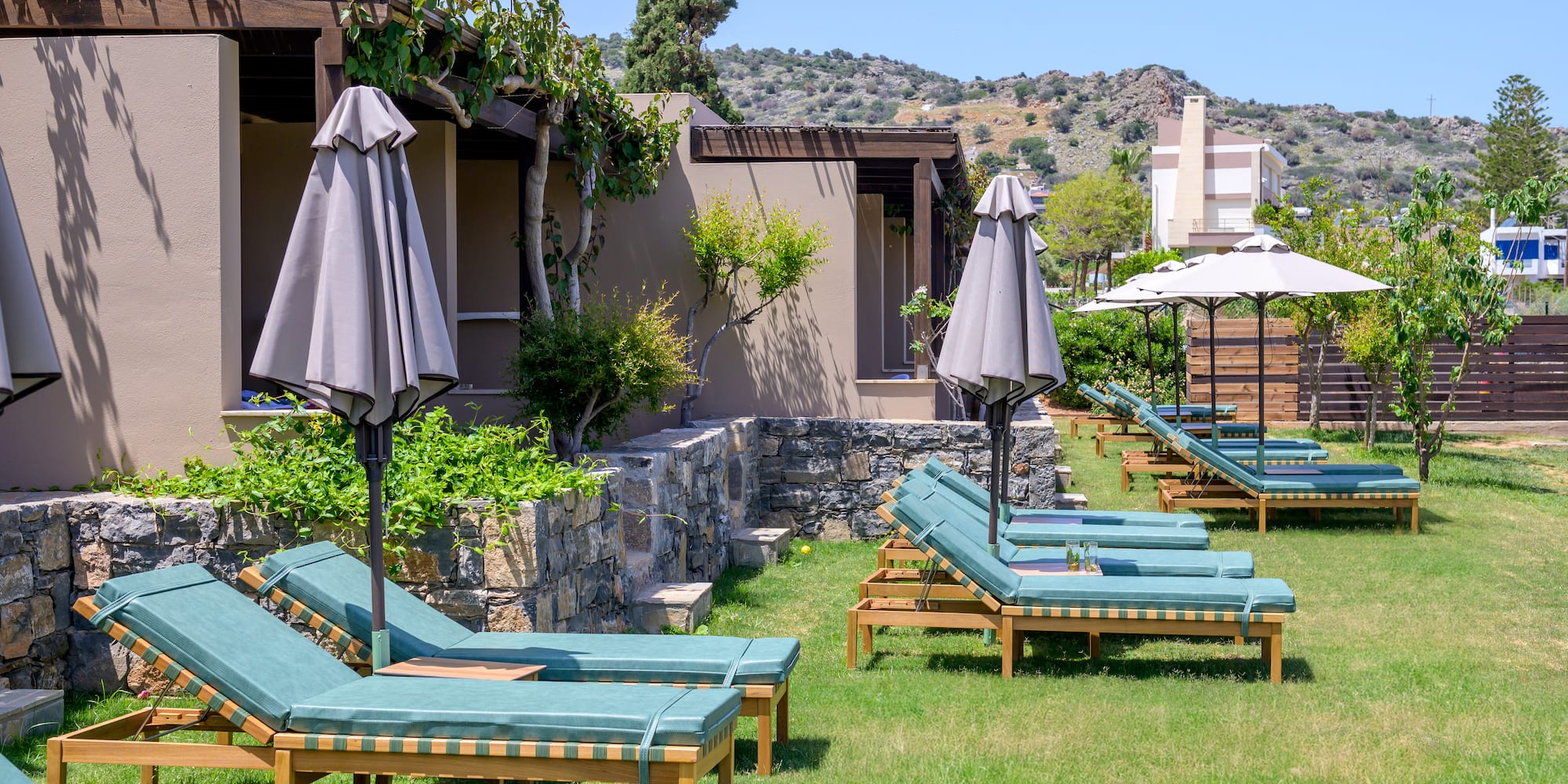 a group of lounge chairs and umbrellas in a yard.