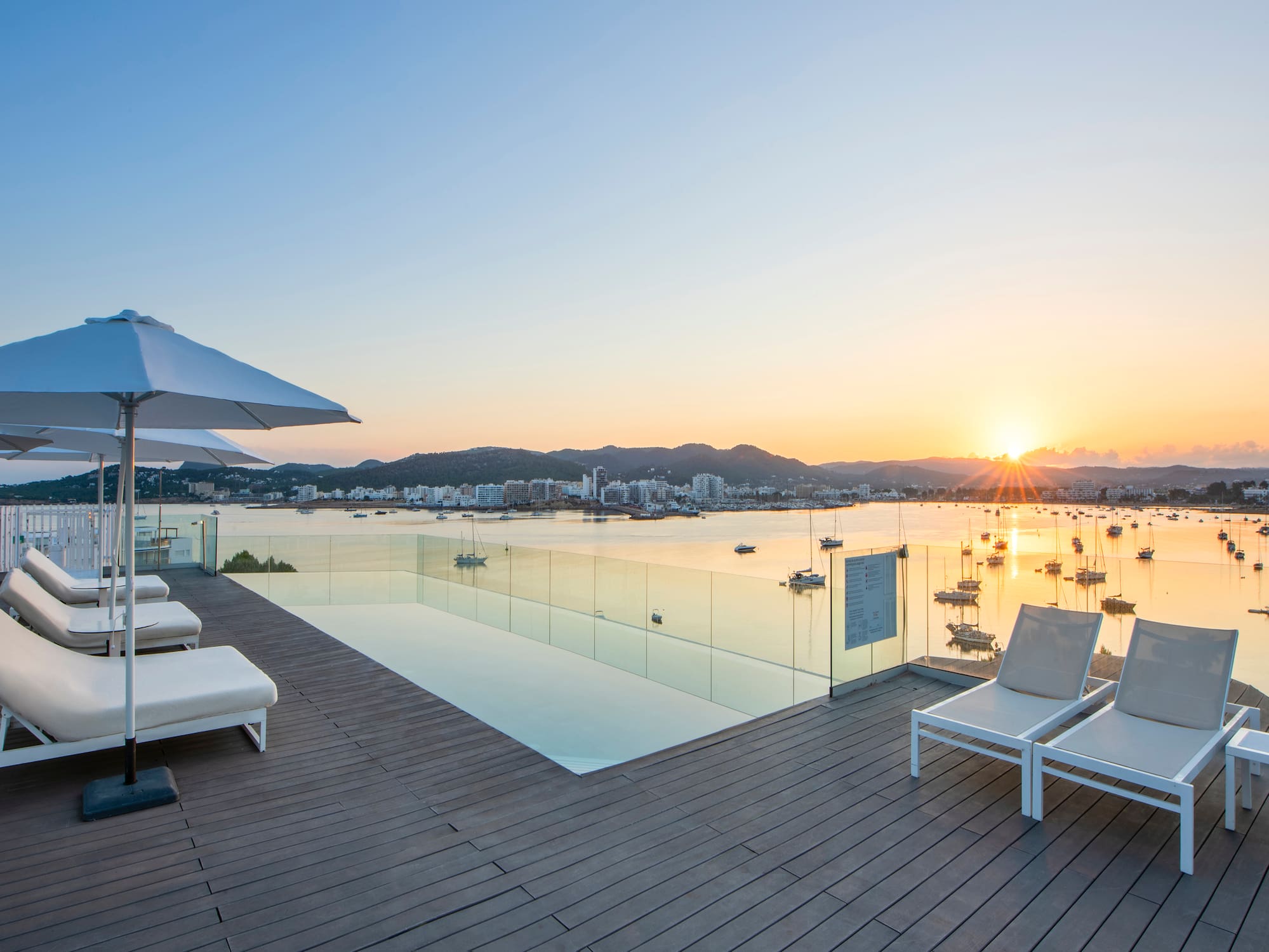 a deck with chairs and a pool overlooking a body of water