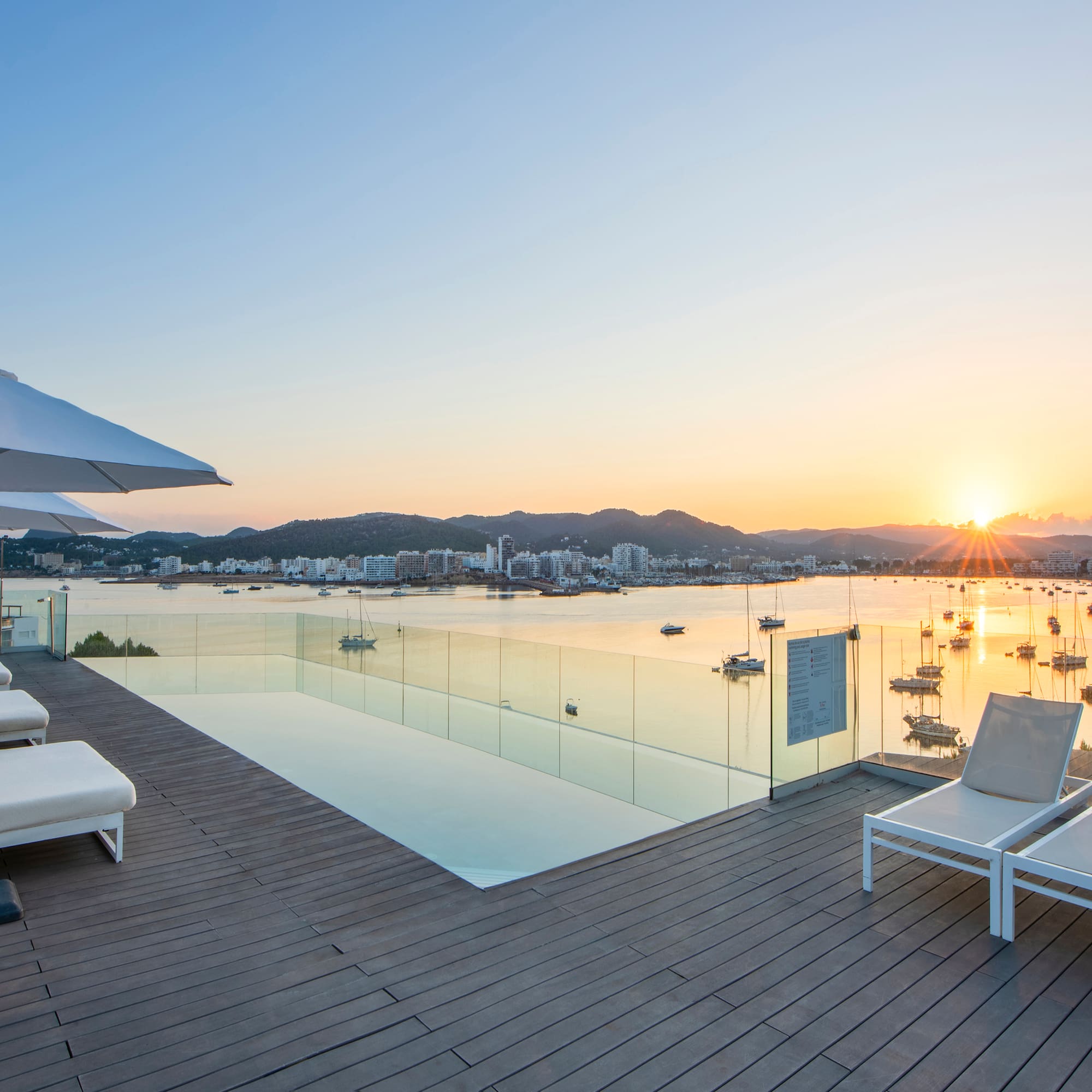 a deck with chairs and a pool overlooking a body of water