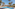 Tropical resort pool with palm trees, sun loungers, and colorful buildings.