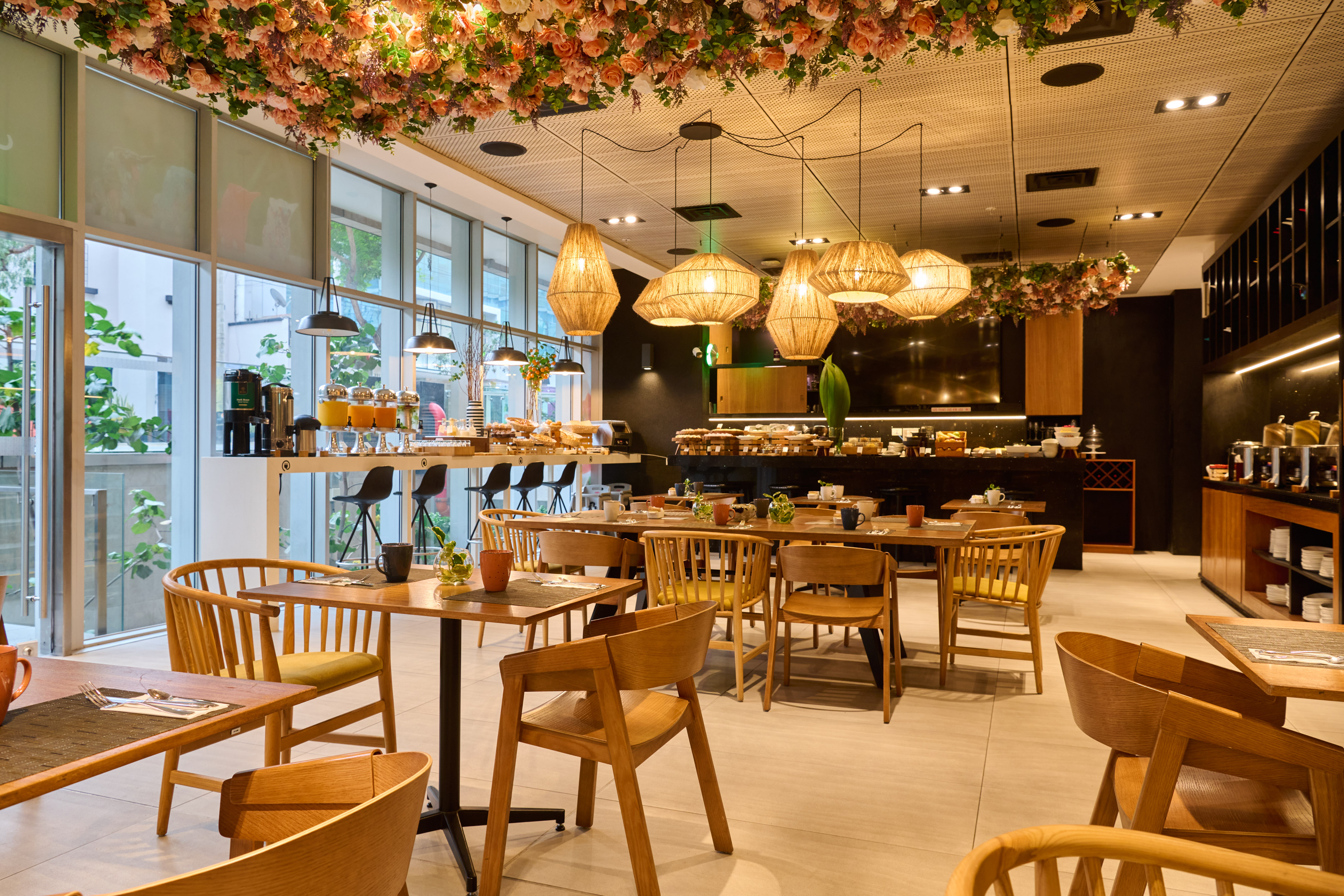 Hotel restaurant interior with floral ceiling, wooden tables, and buffet.