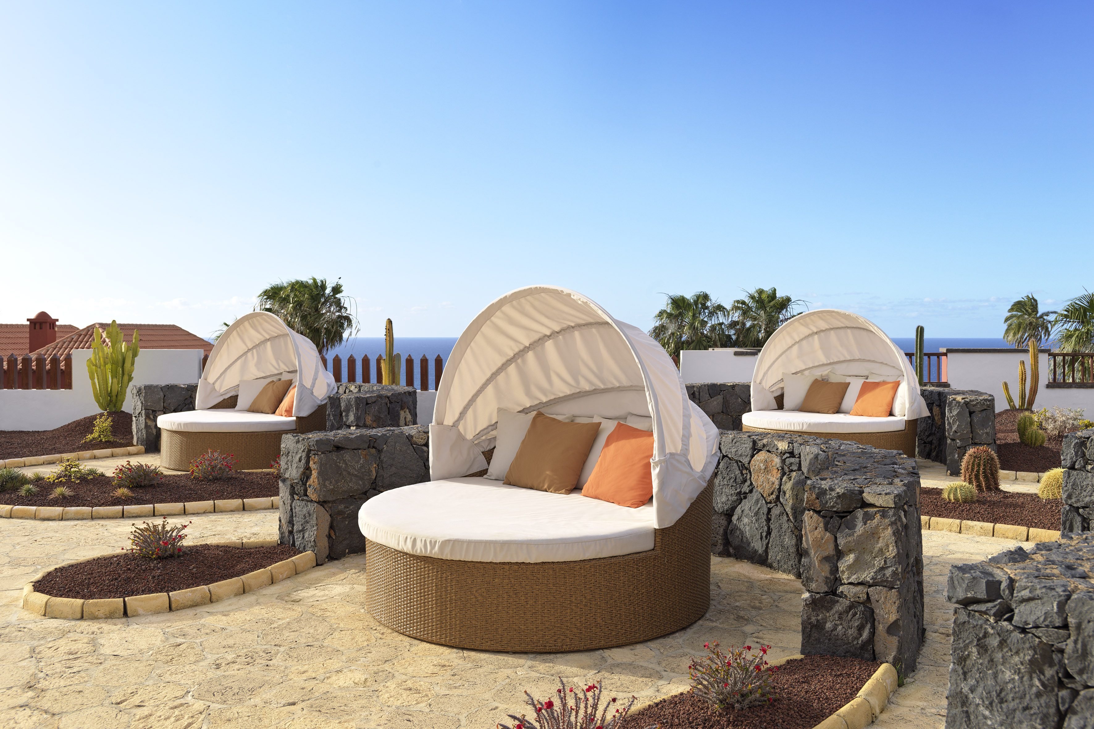 Relaxing outdoor daybeds with ocean views at a sunny resort.