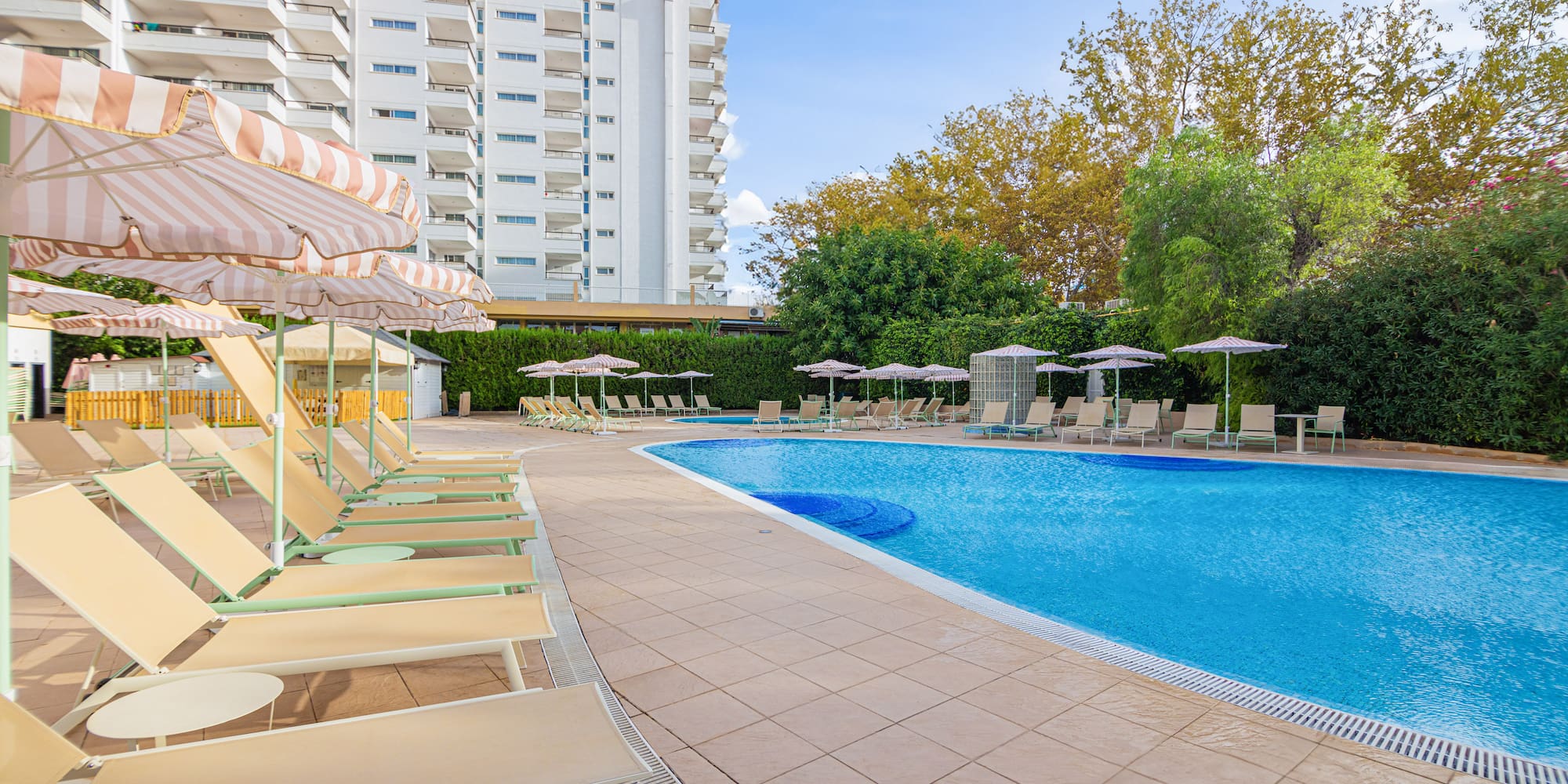 a pool with chairs and umbrellas by a building