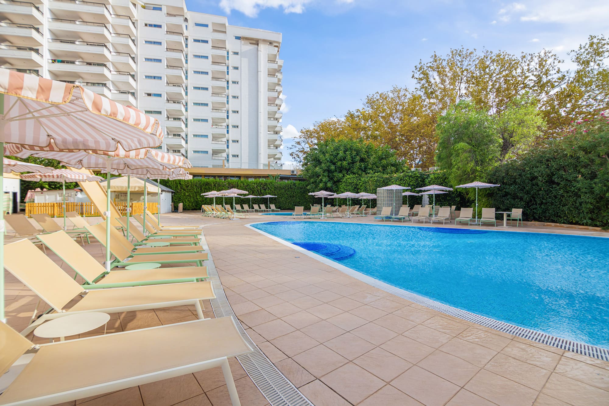 a pool with chairs and umbrellas by a building