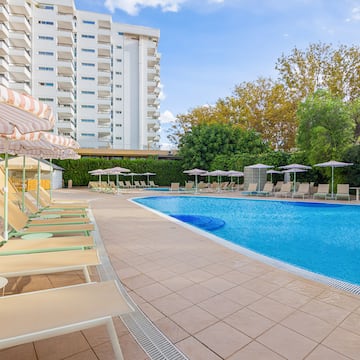 a pool with chairs and umbrellas by a building