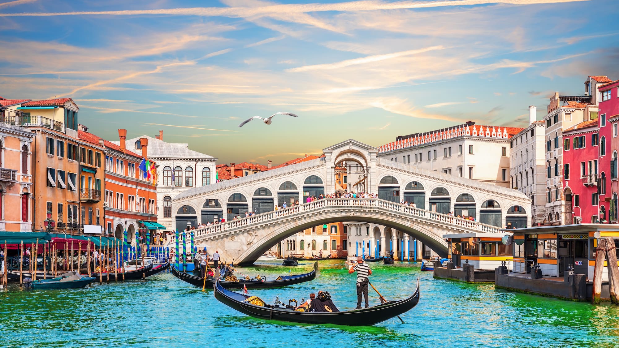 a group of people in a boat on a canal with Rialto Bridge in the background