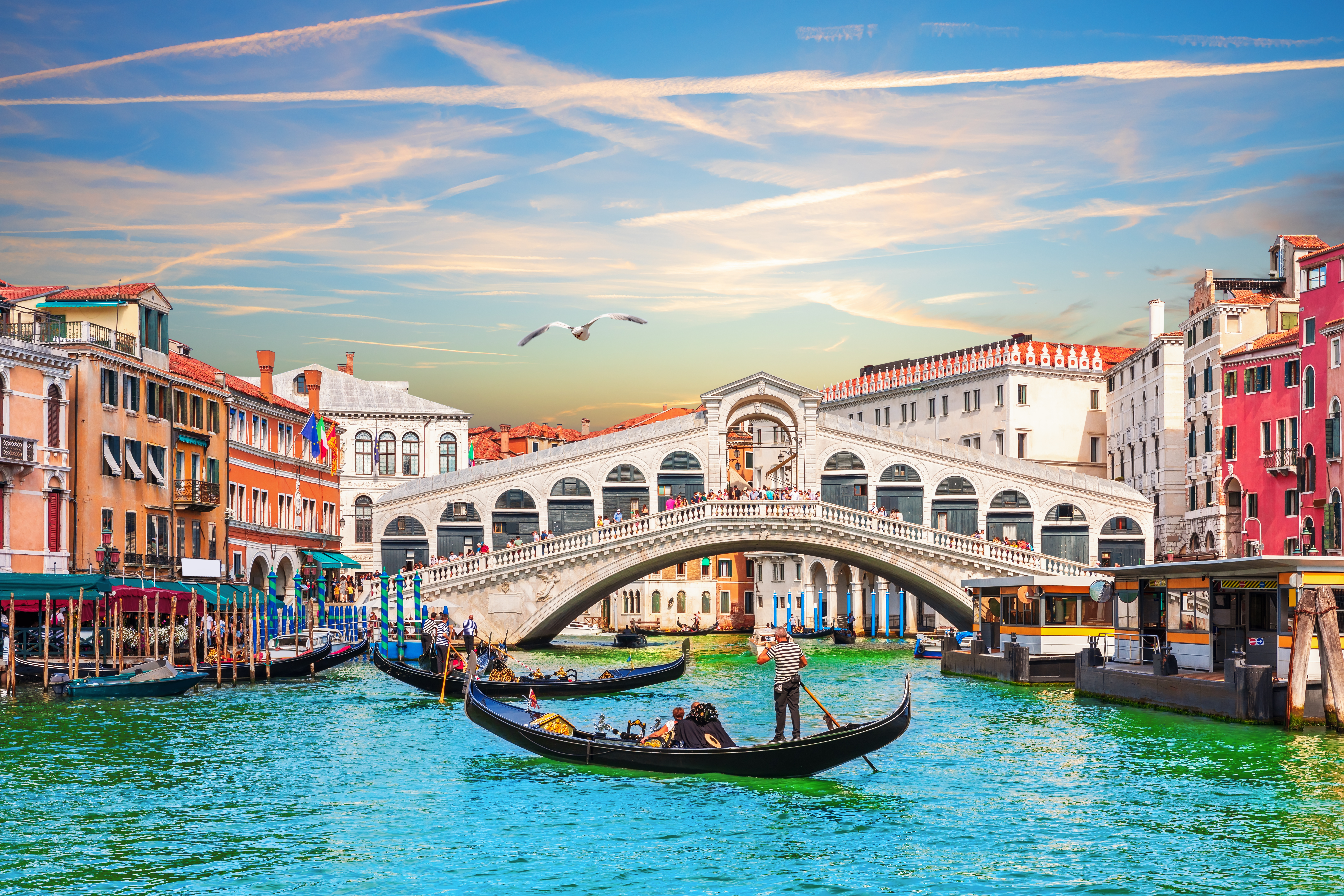 a group of people in a boat on a canal with Rialto Bridge in the background
