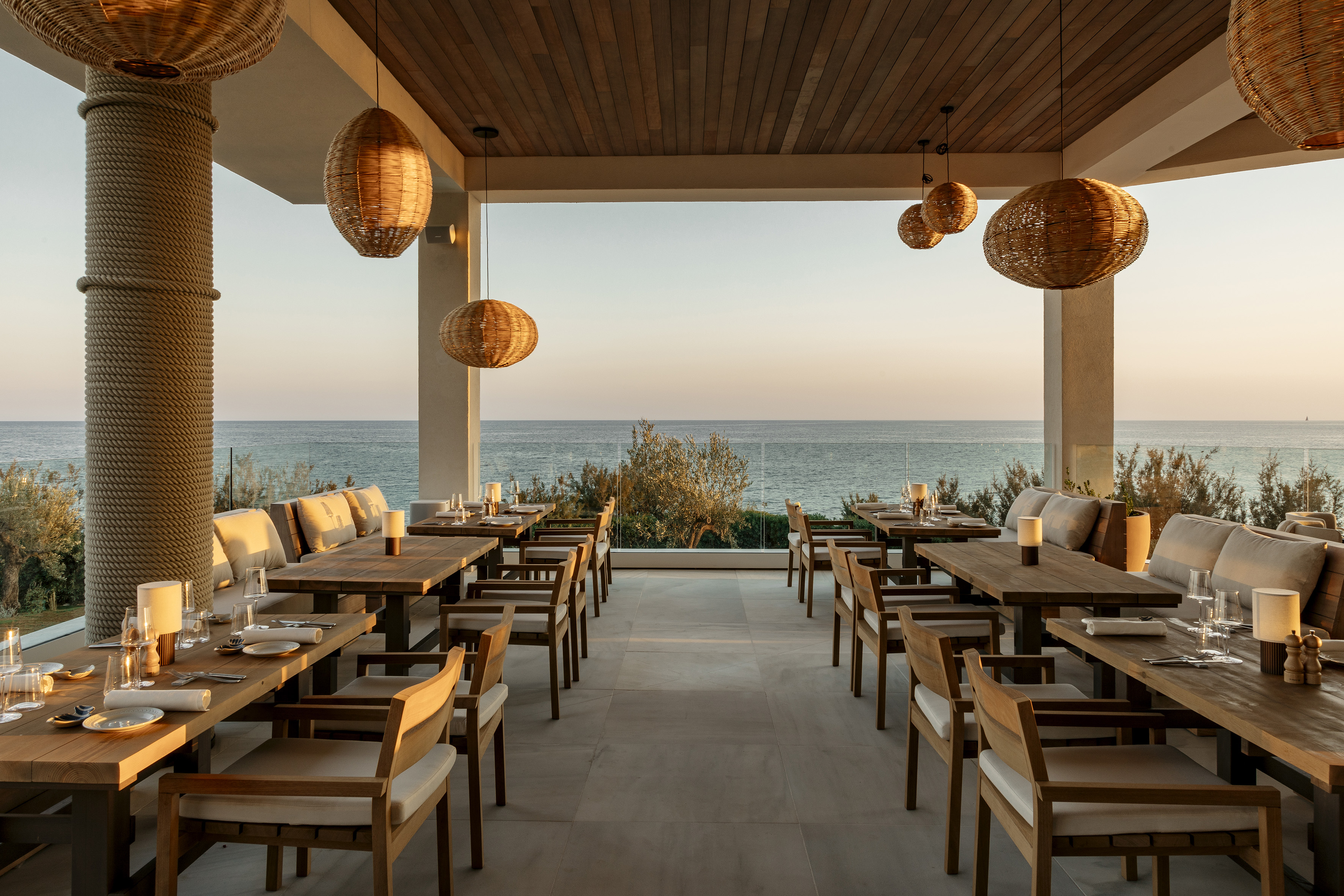 Oceanfront outdoor dining restaurant at sunset with wicker lights.
