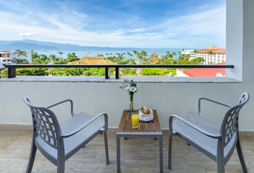 a table and chairs on a balcony overlooking a body of water