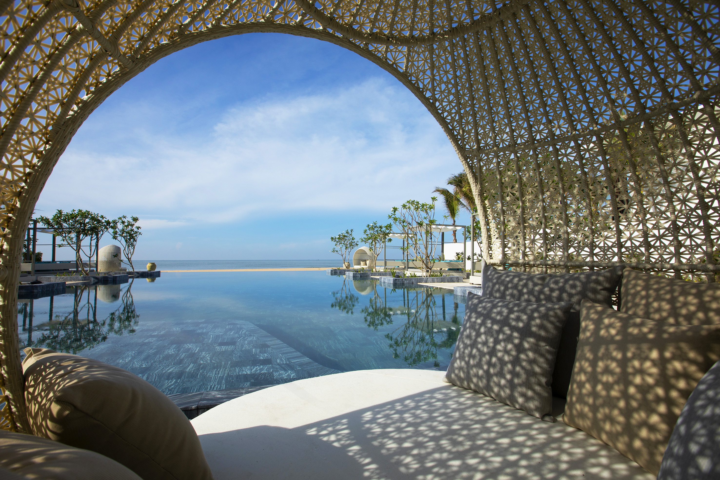 Luxury resort cabana with infinity pool, ocean view, and blue sky.