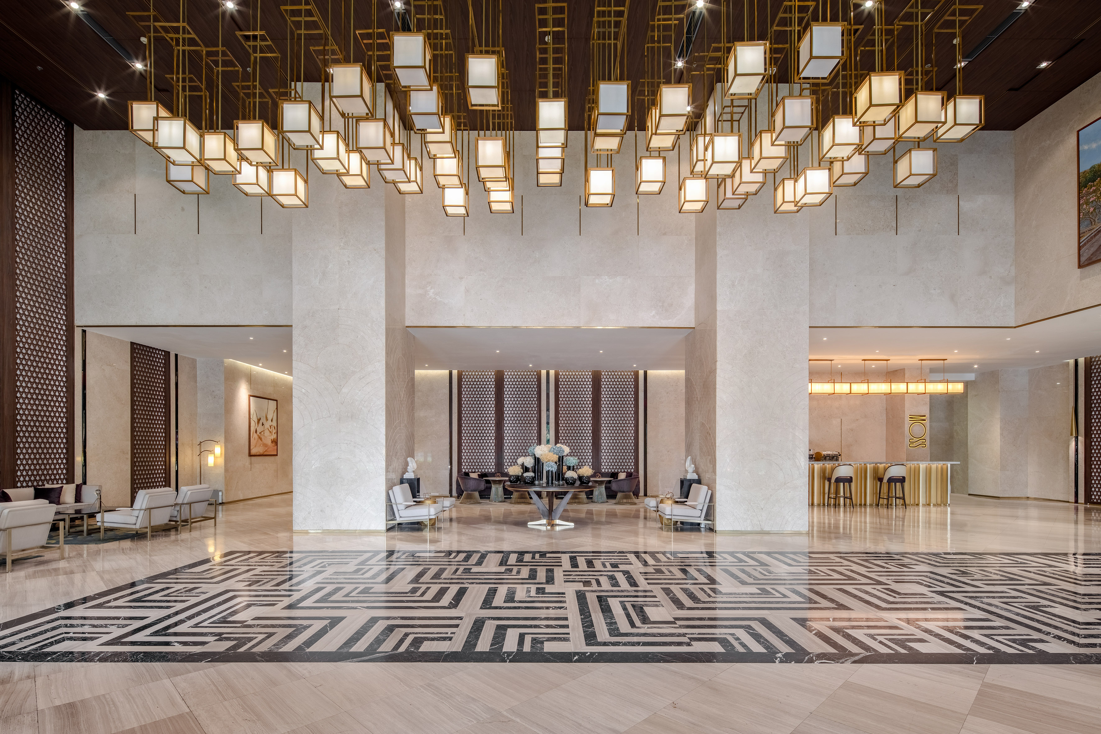 Grand luxury hotel lobby with gold cube chandeliers and geometric marble floor.