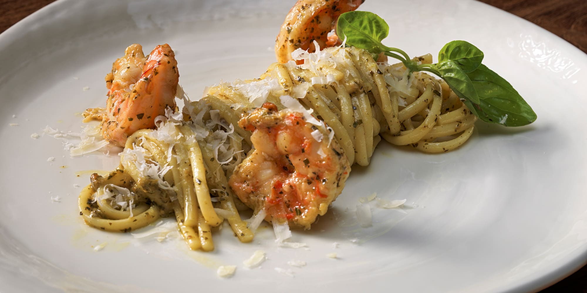 a plate of pasta with shrimp and basil