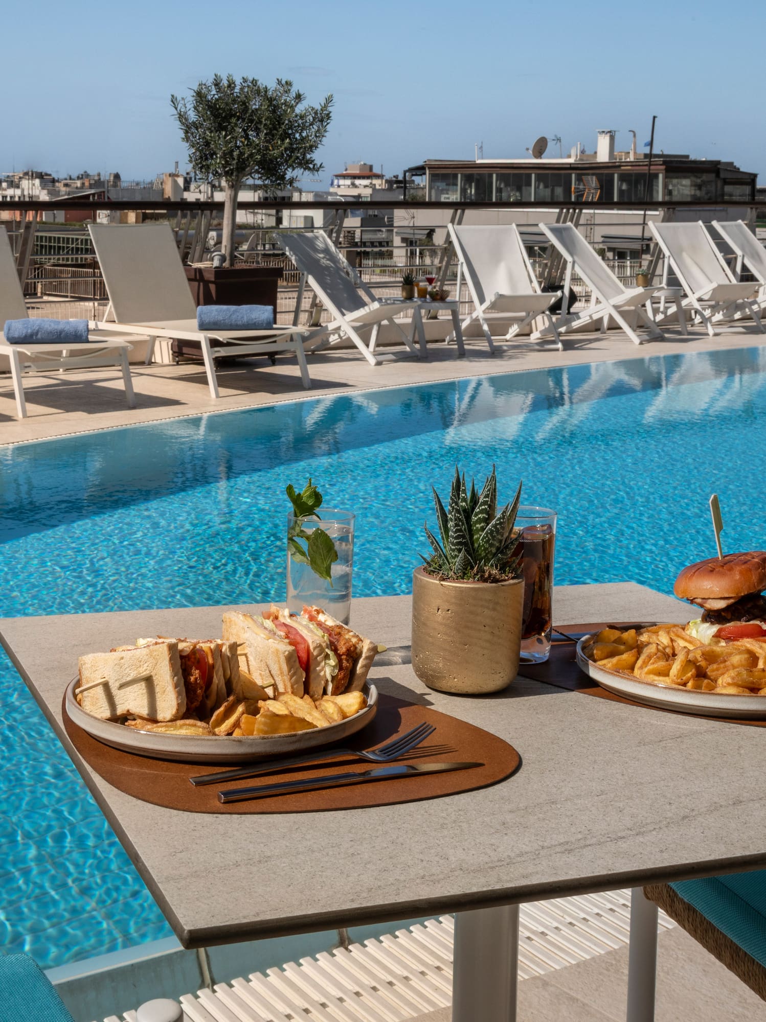 Rooftop pool dining with burger, club sandwich, and fries.