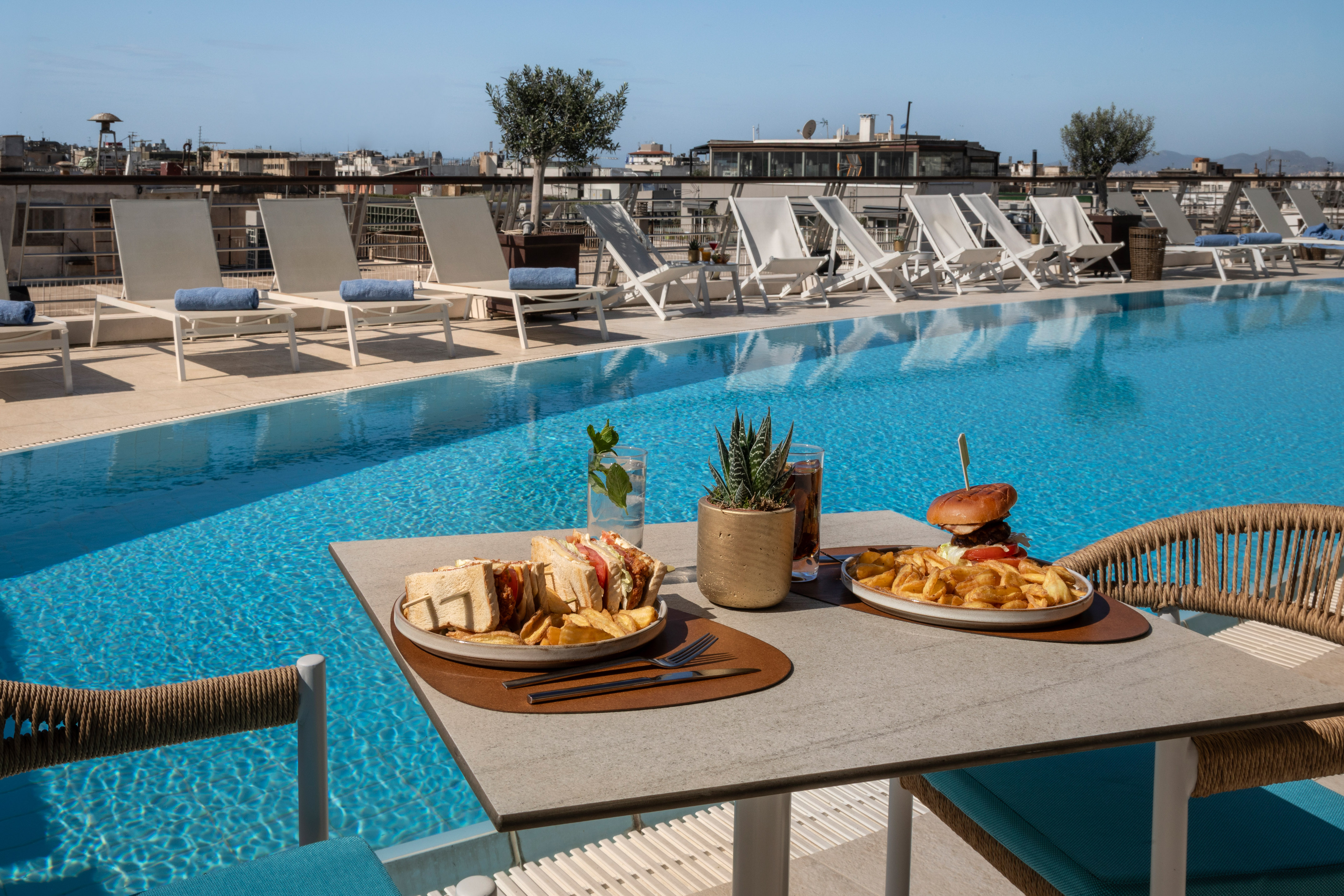 Rooftop pool dining with burger, club sandwich, and fries.