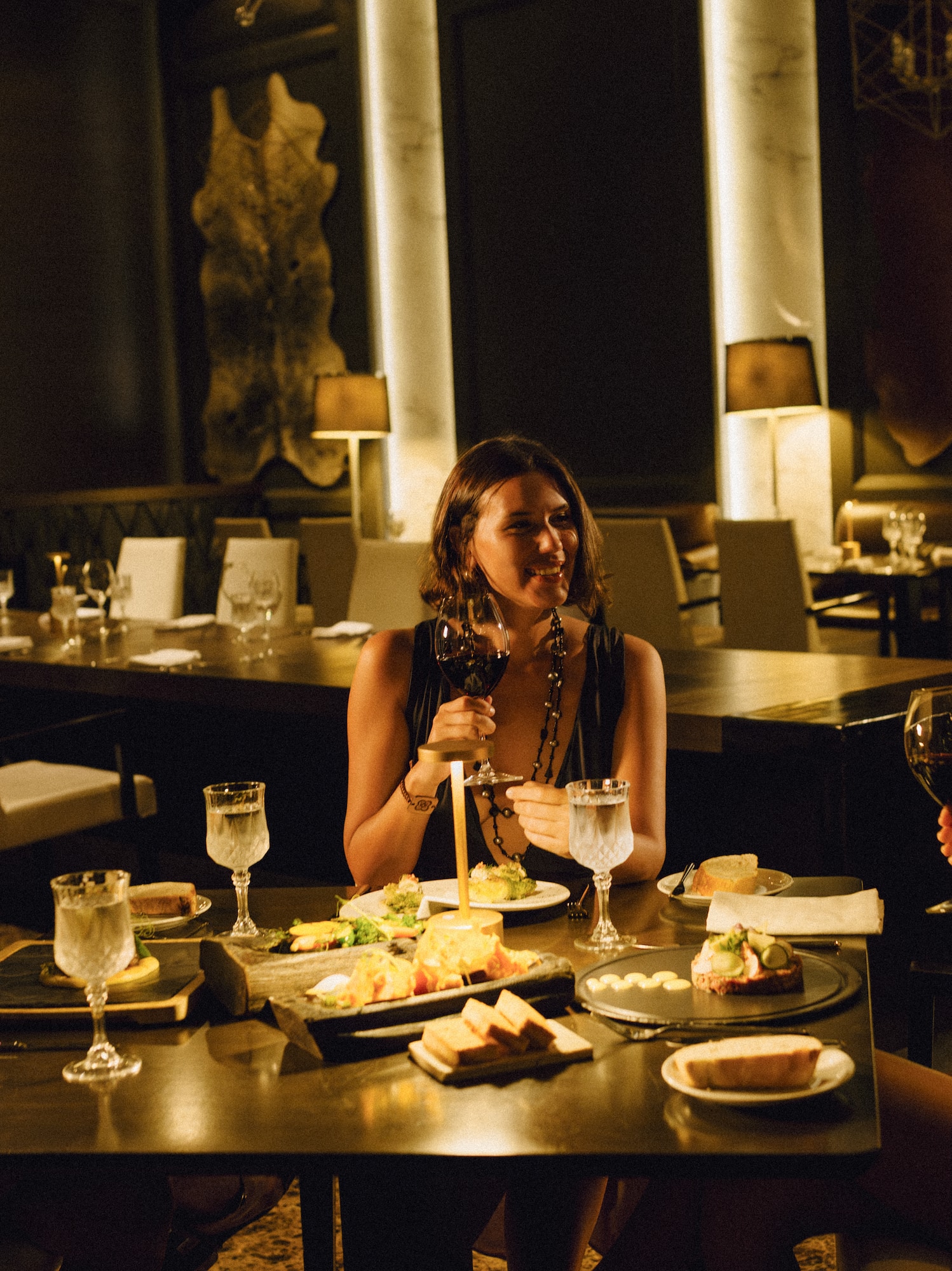 Three friends enjoying wine and dinner with a server in an upscale restaurant.