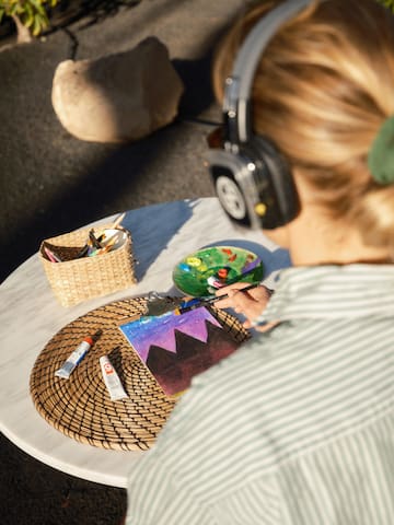 a woman wearing headphones painting on a table