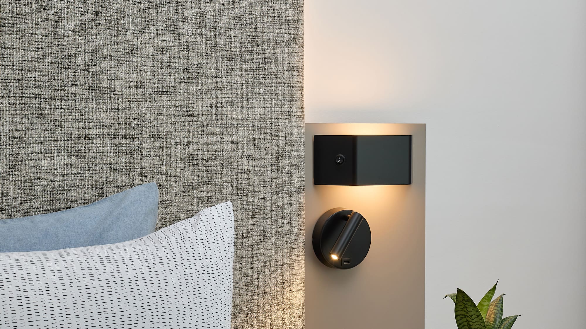 a small table with a plant on it next to a bed