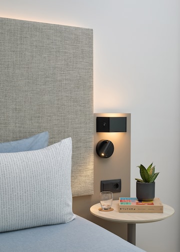 a small table with a plant on it next to a bed