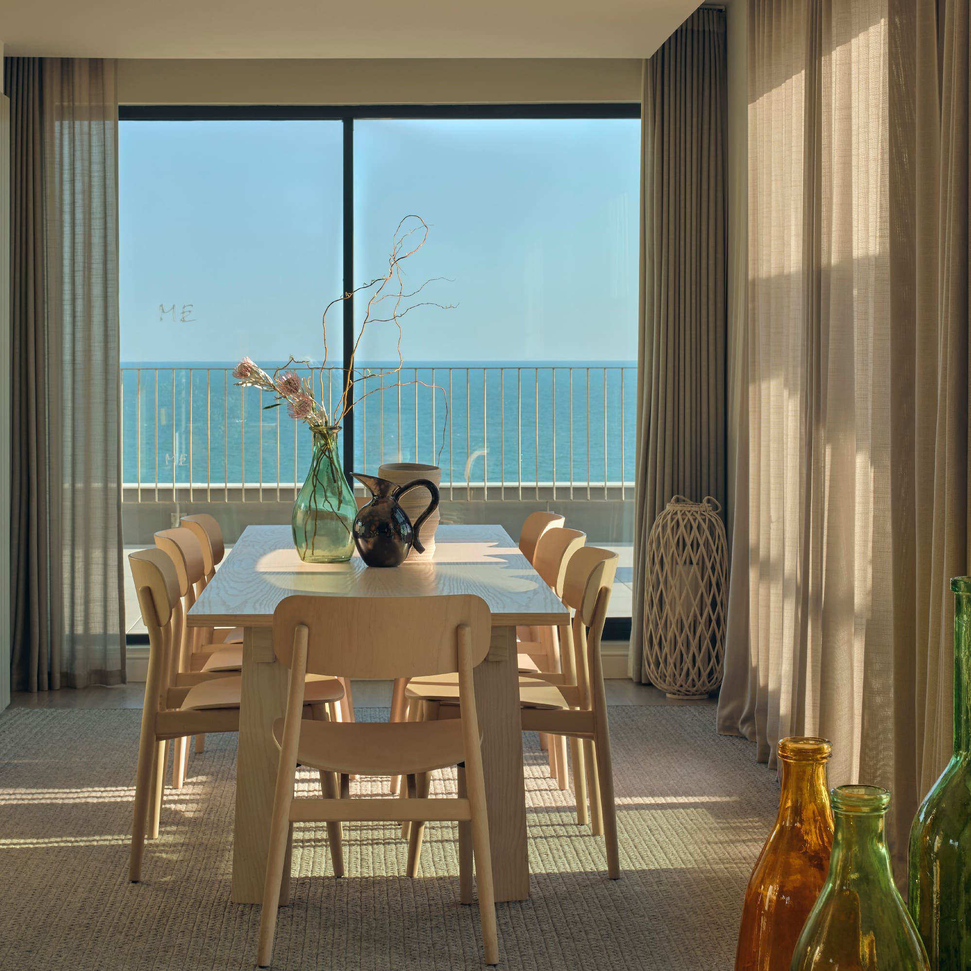 a dining table with chairs and vases in front of a window