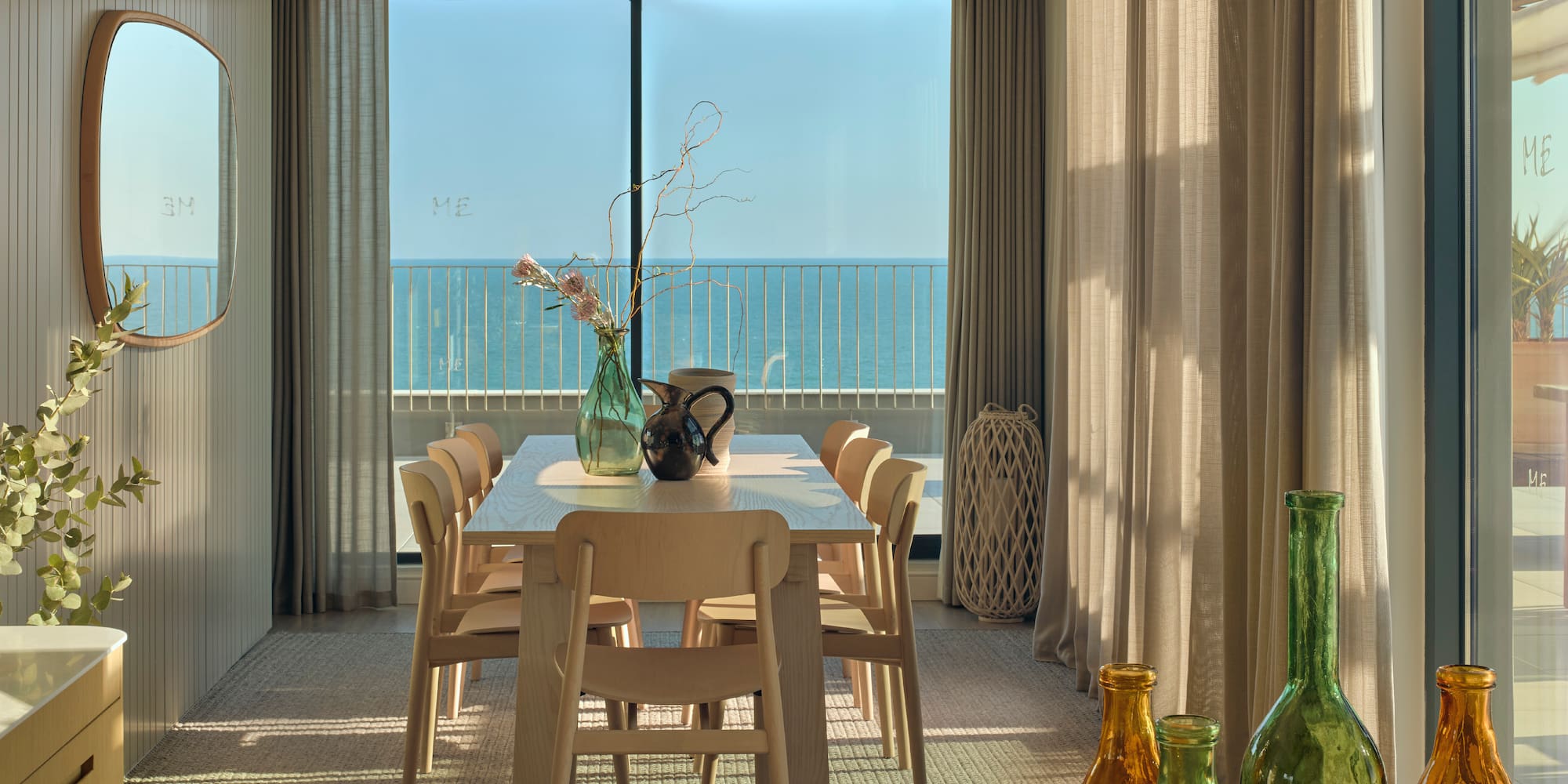 a dining table with chairs and vases in front of a window