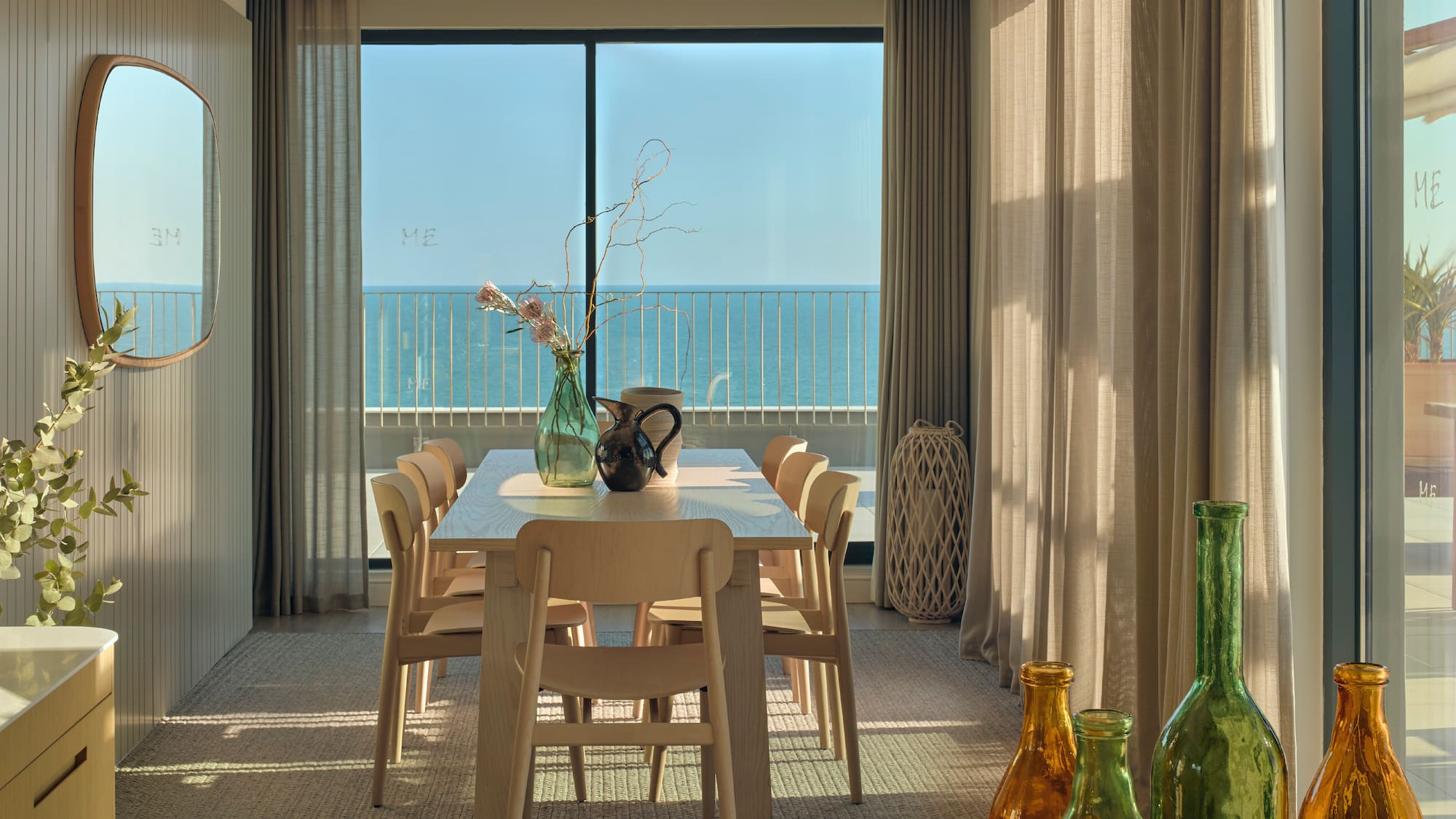 a dining table with chairs and vases in front of a window