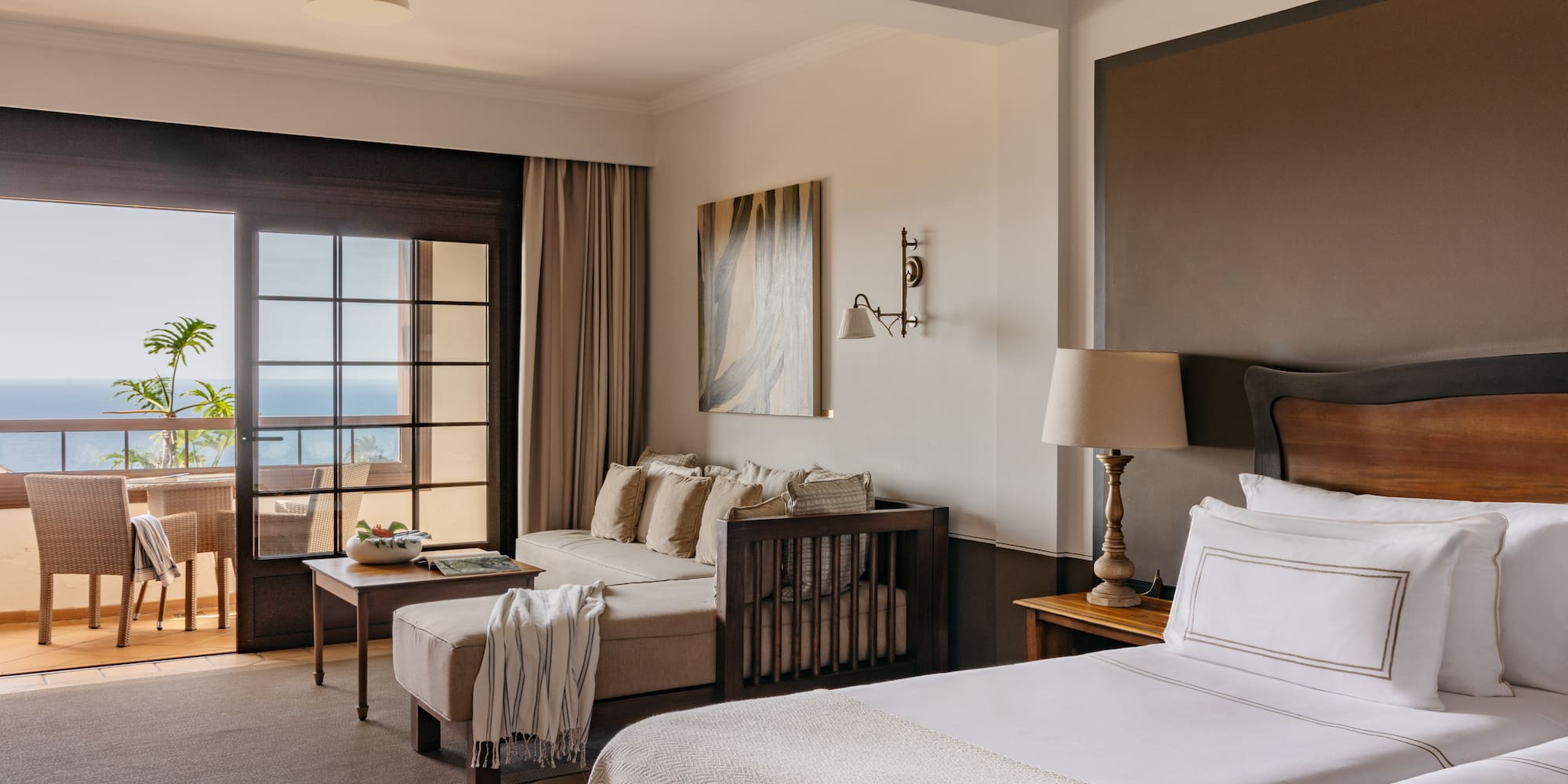 Resort suite with ocean view balcony, twin beds, and daybed living area.