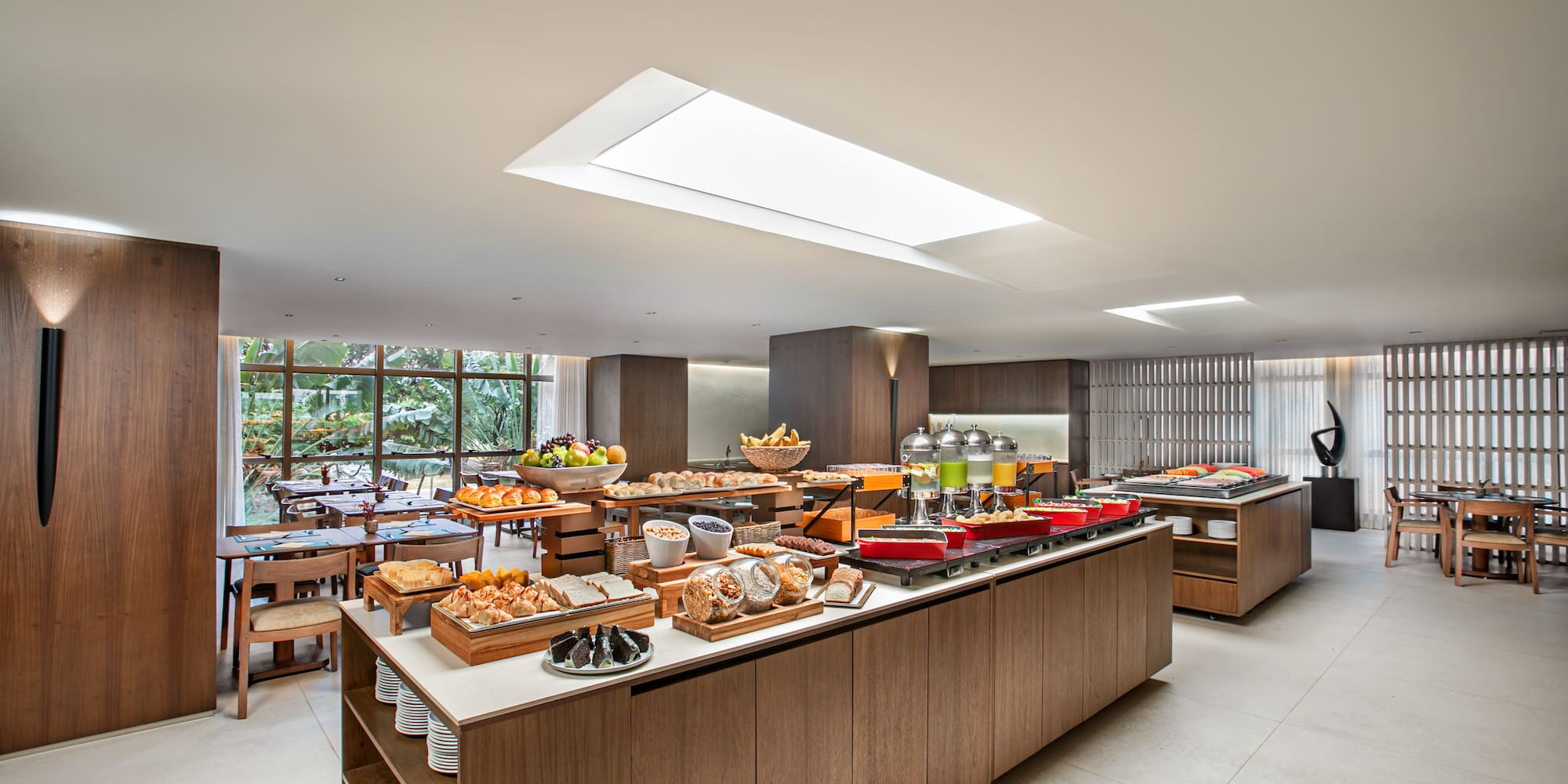 Modern hotel restaurant buffet with fresh breakfast foods, pastries, and fruit.
