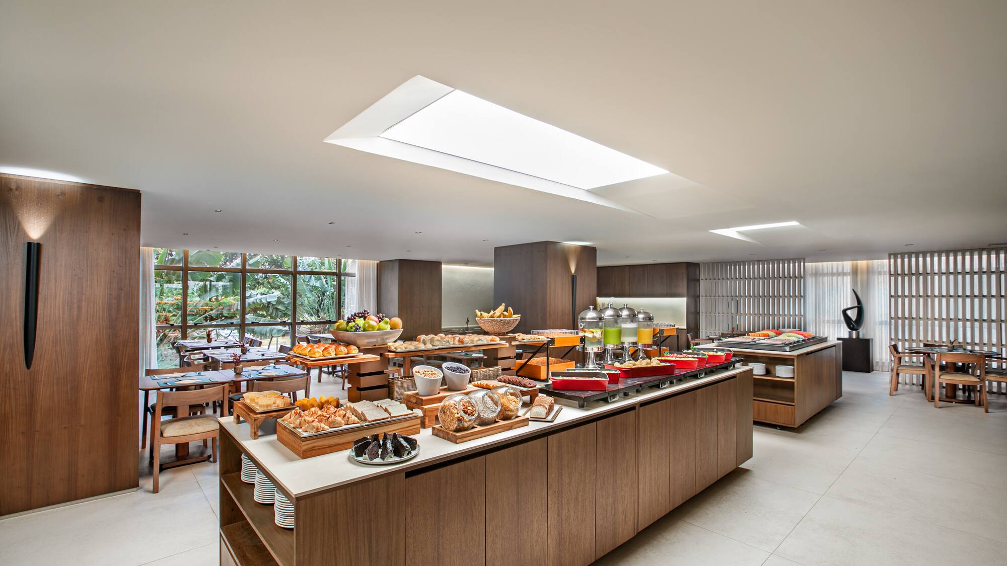 Modern hotel restaurant buffet with fresh breakfast foods, pastries, and fruit.