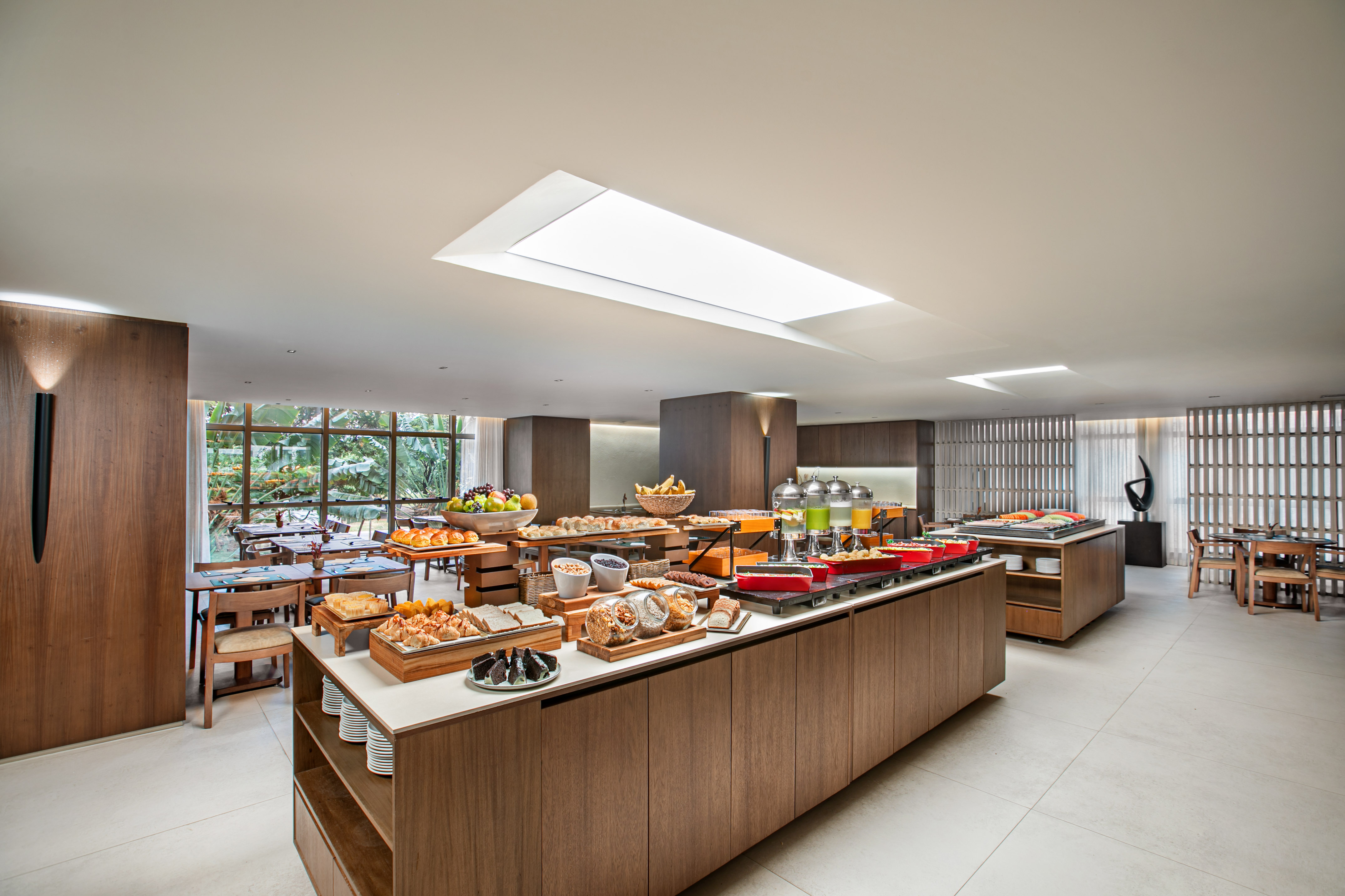 Modern hotel restaurant buffet with fresh breakfast foods, pastries, and fruit.