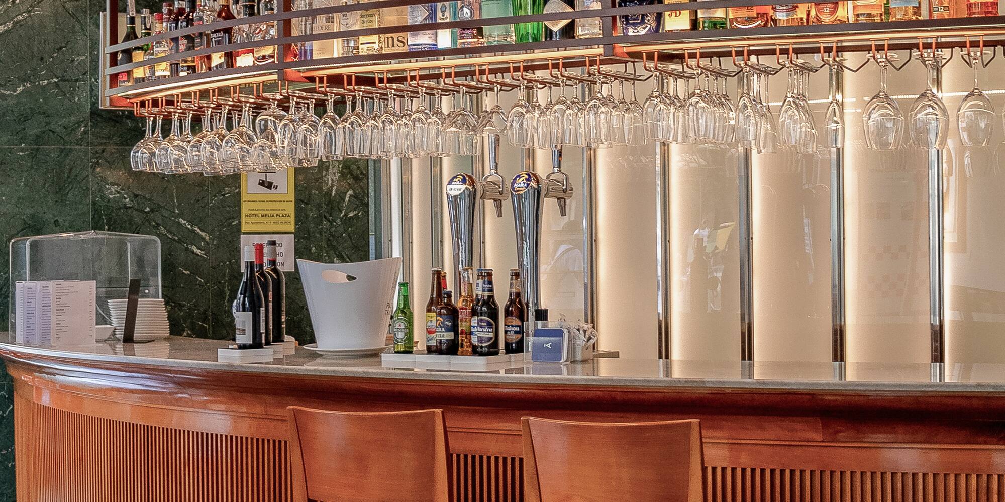 a bar with wine glasses over the bar