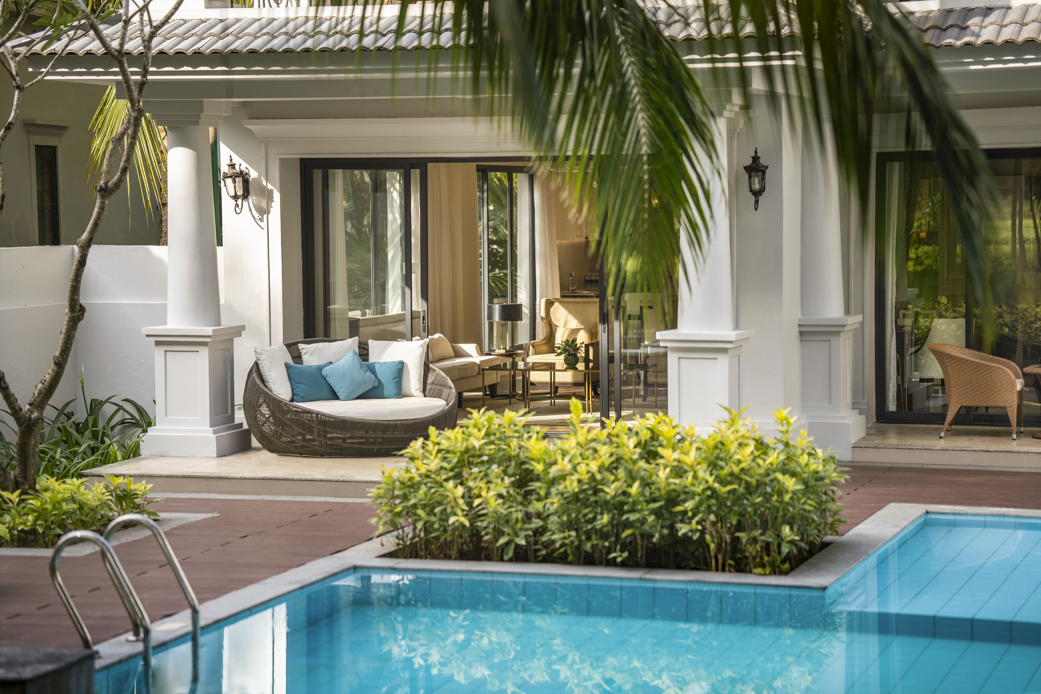 Resort patio with private swimming pool, outdoor daybed, and lush tropical plants.